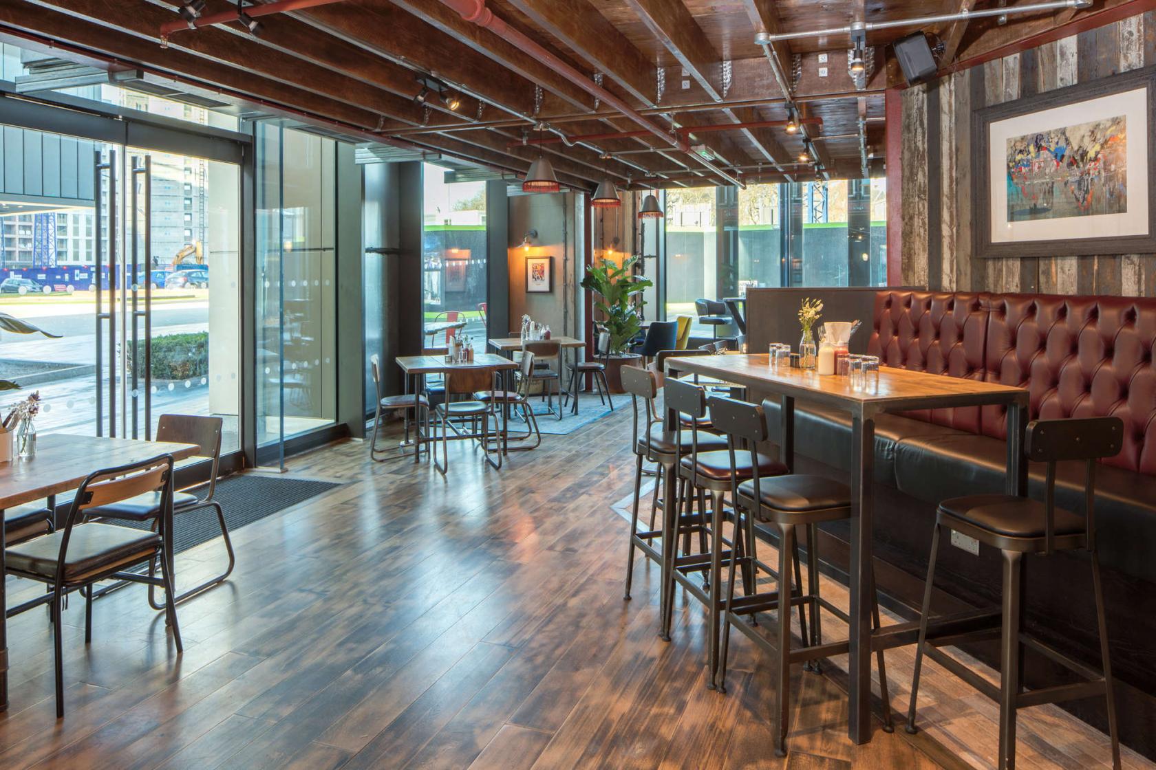 A pub dining room with tufted banquette seating, wood floors, and exposed beams at Lockhouse.