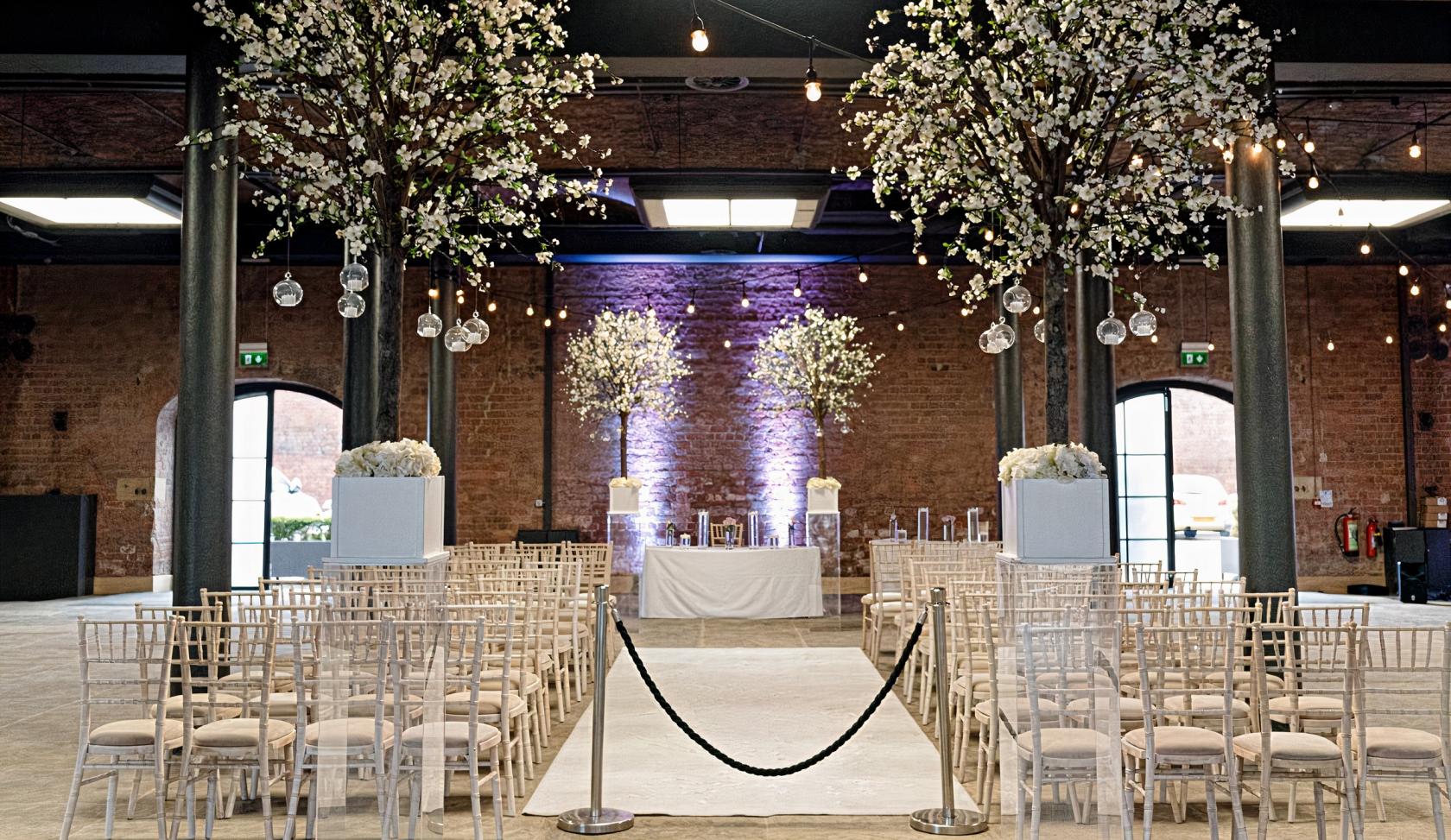 An event space with exposed brick walls, chiavari chairs, and large floral centerpieces at Titanic Hotel West Bay.