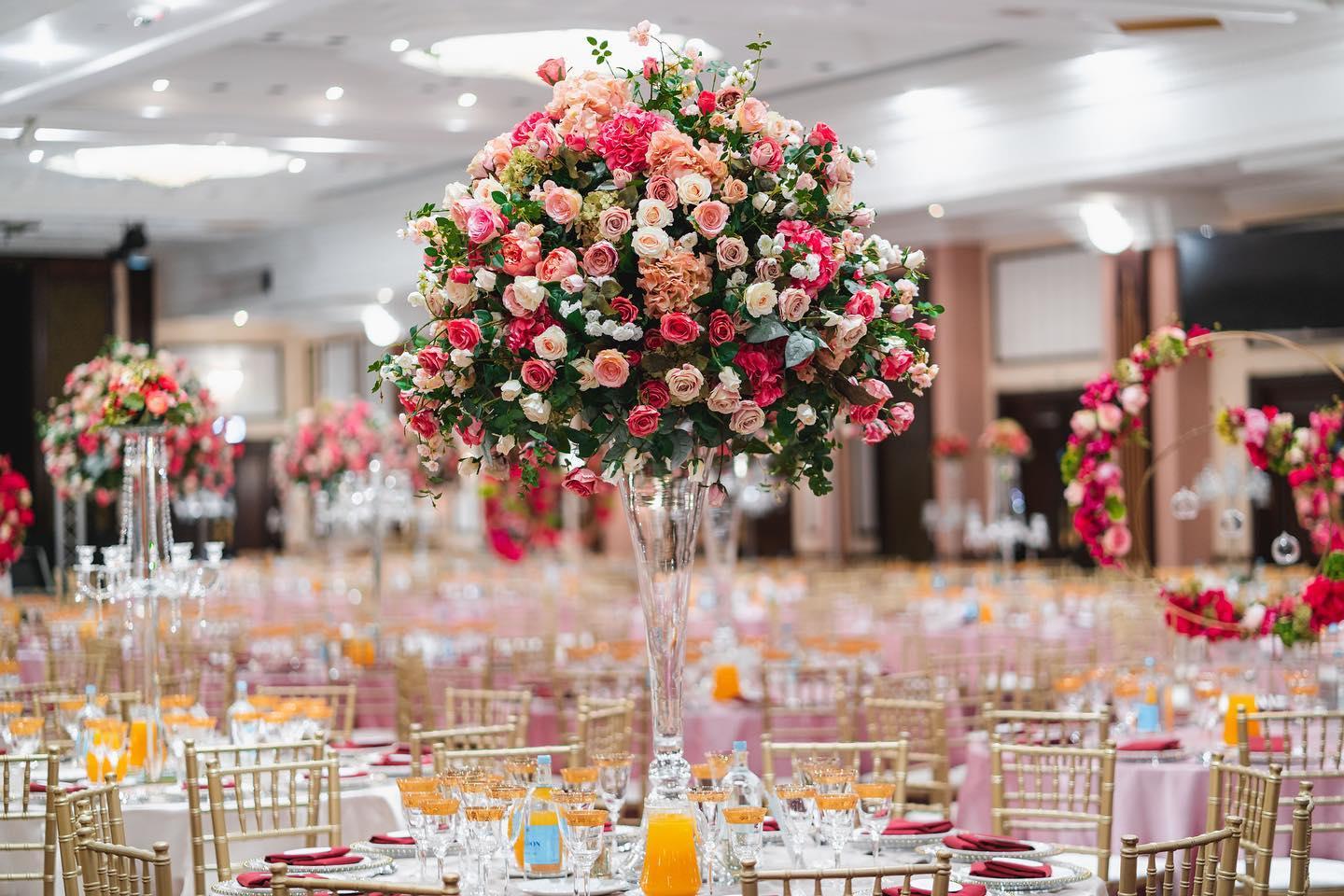 A banquet hall with tall floral centerpieces, gold chairs, and round tables set for an event at National Motorcycle Museum.