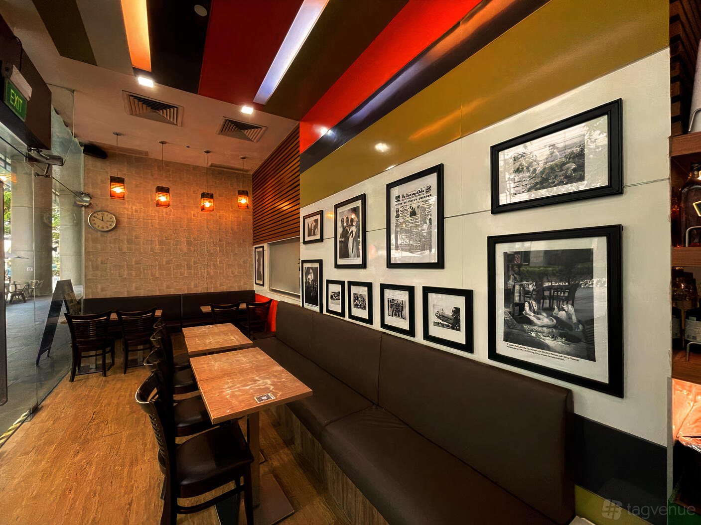A cafe with wooden tables, brown banquette seating, and a gallery wall of black-and-white photos at Anglo Indian Cafe & Bar - Shenton Way.