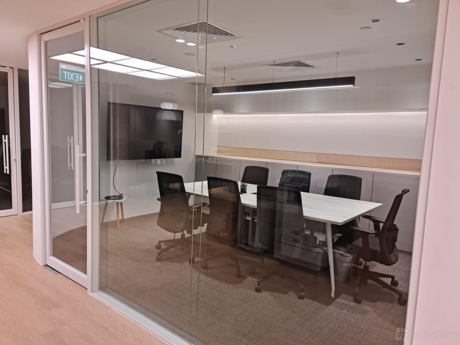 A glass-walled boardroom with a long white table, black swivel chairs, and a wall-mounted TV at N9 Offices (City Hall).