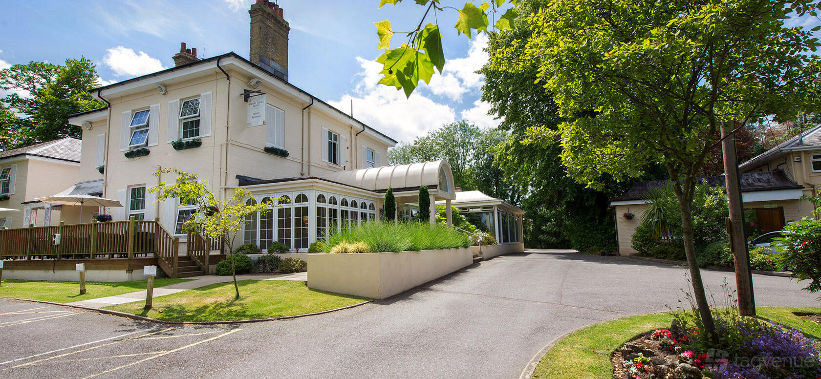 A versatile event space with a white facade, glass conservatory entry, and landscaped driveway at Forest Lodge Hotel.