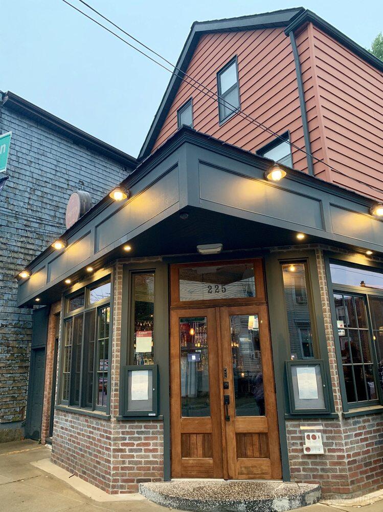 A restaurant with large front windows, wood framed entrance, and exterior string lighting at The Hutton Restaurant and Bar.
