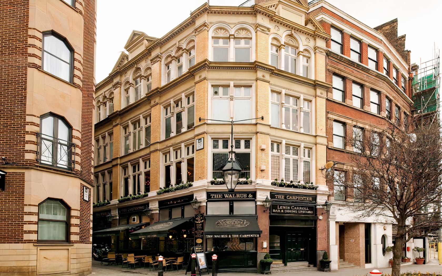 A traditional pub with an ornate Victorian facade, large windows, and outdoor seating at The Walrus and Carpenter.