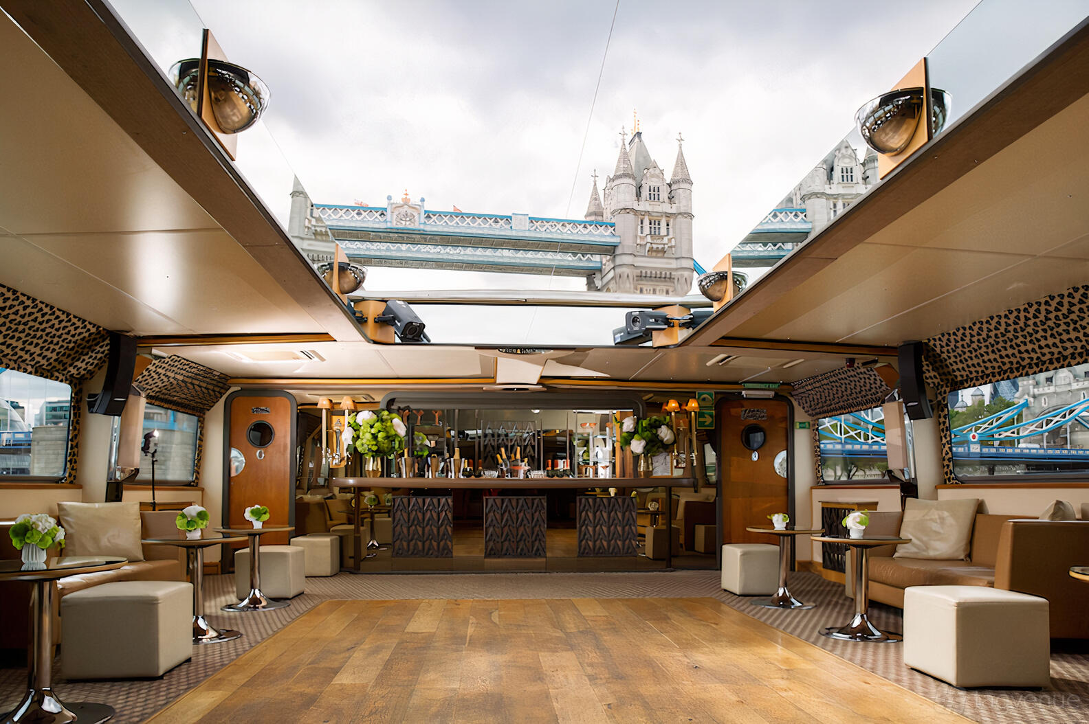 A yacht event space with open roof, wooden floors, lounge seating, and a bar at Woods Silver Fleet Silver Barracuda.