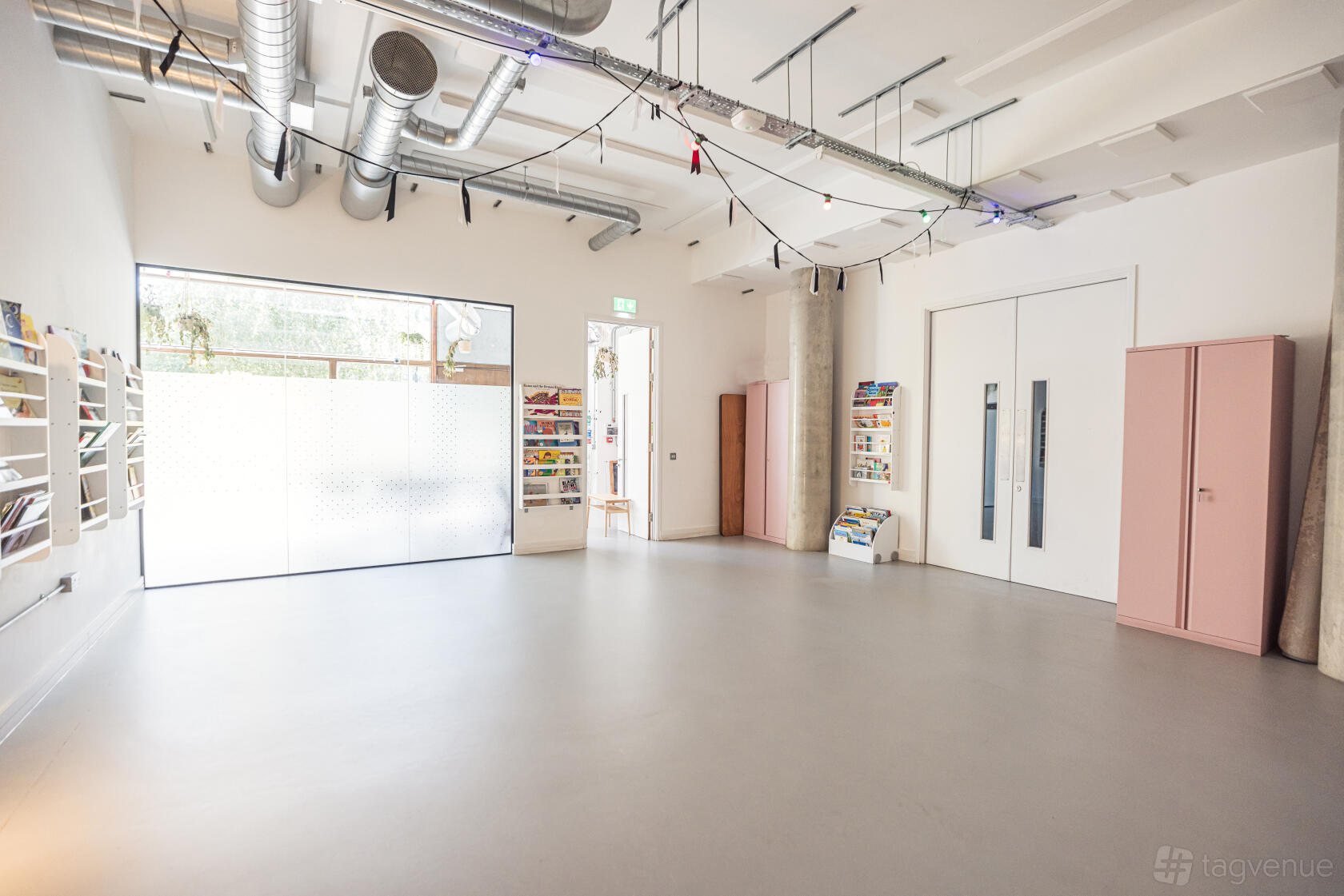A creative space with polished concrete floors, exposed ducts, and large frosted windows at Hackney Showroom.