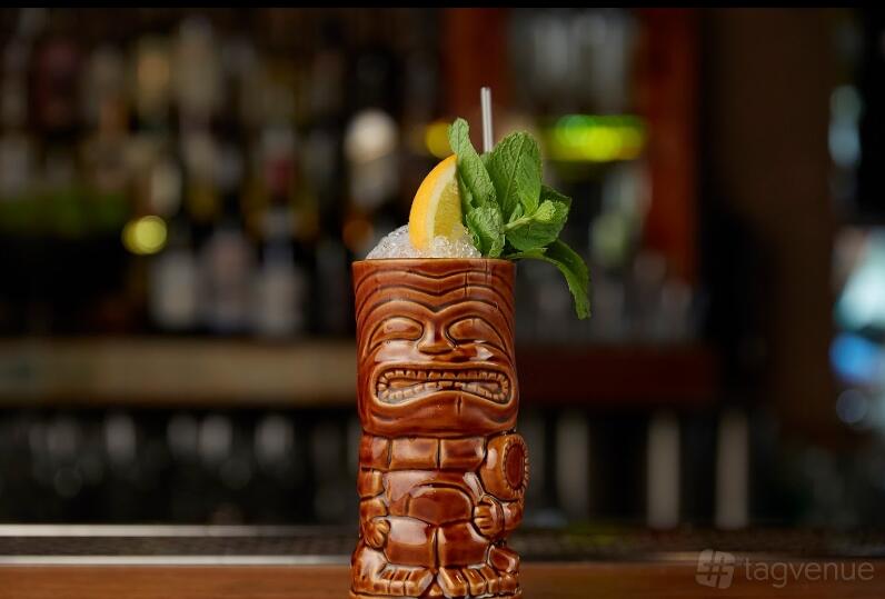 A cocktail garnished with orange and mint served in a tiki mug at Stitch Bar.