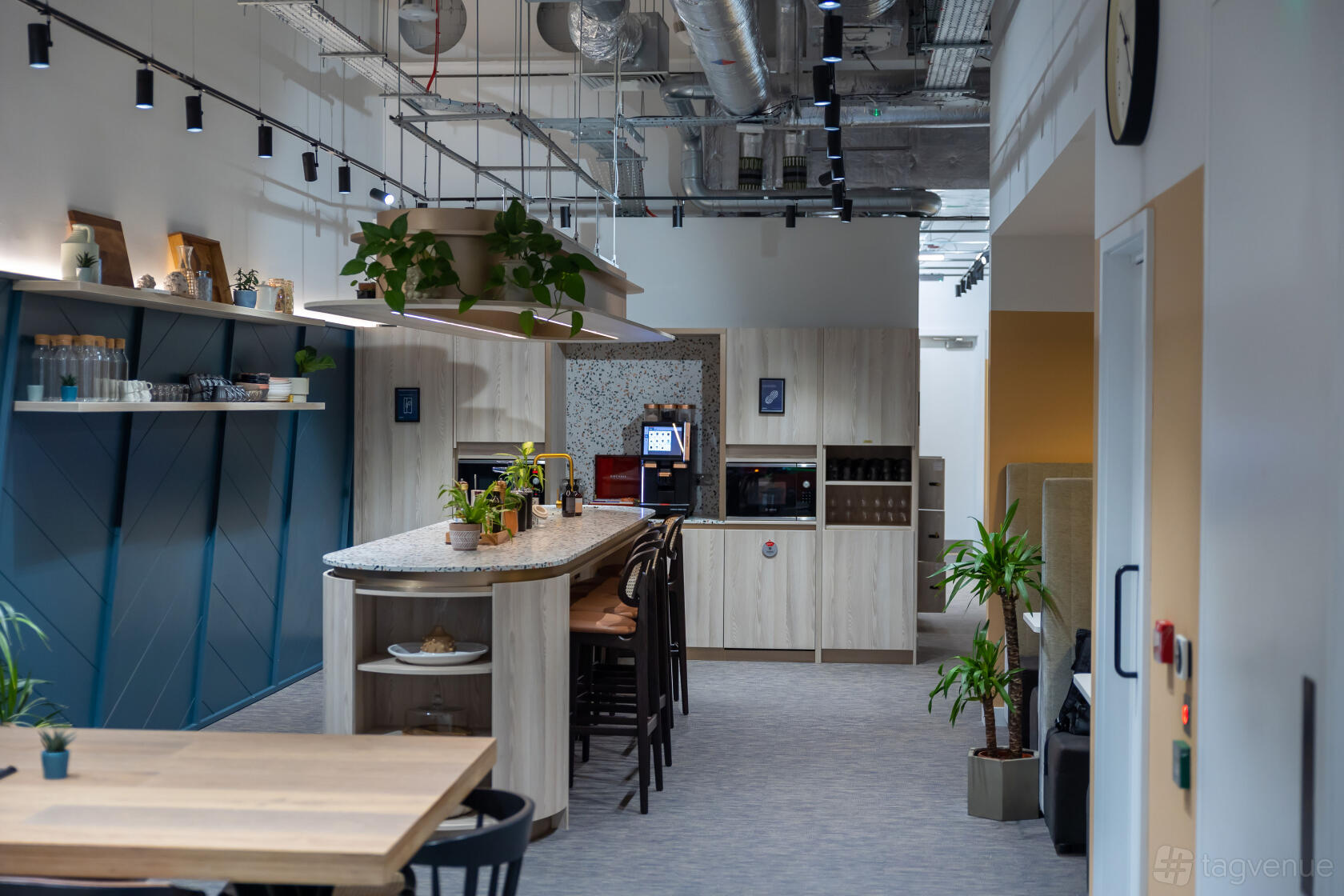 An event venue with a central island counter, open shelving, and exposed ductwork at UNTIL Soho.
