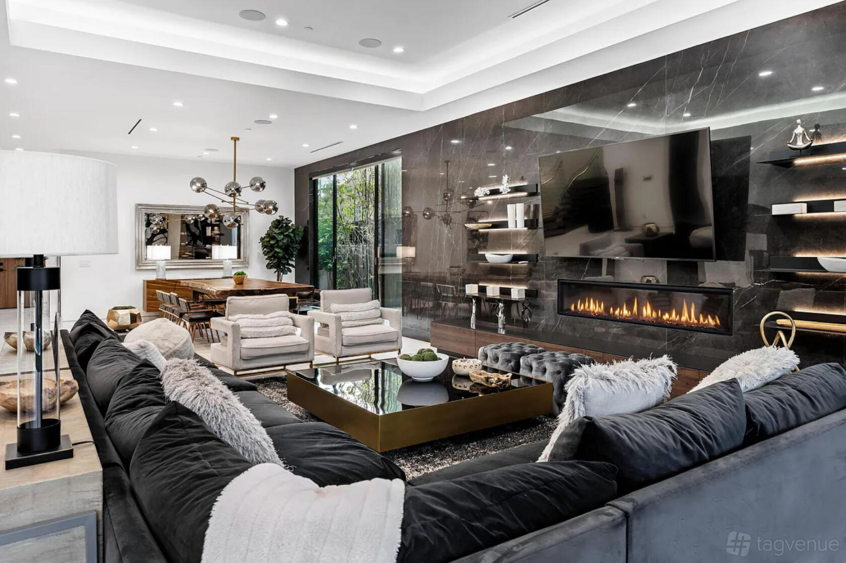 A spacious apartment living area with a large sectional sofa, marble fireplace, built-in shelves, and floor-to-ceiling windows at Exquisite Modern Villa.