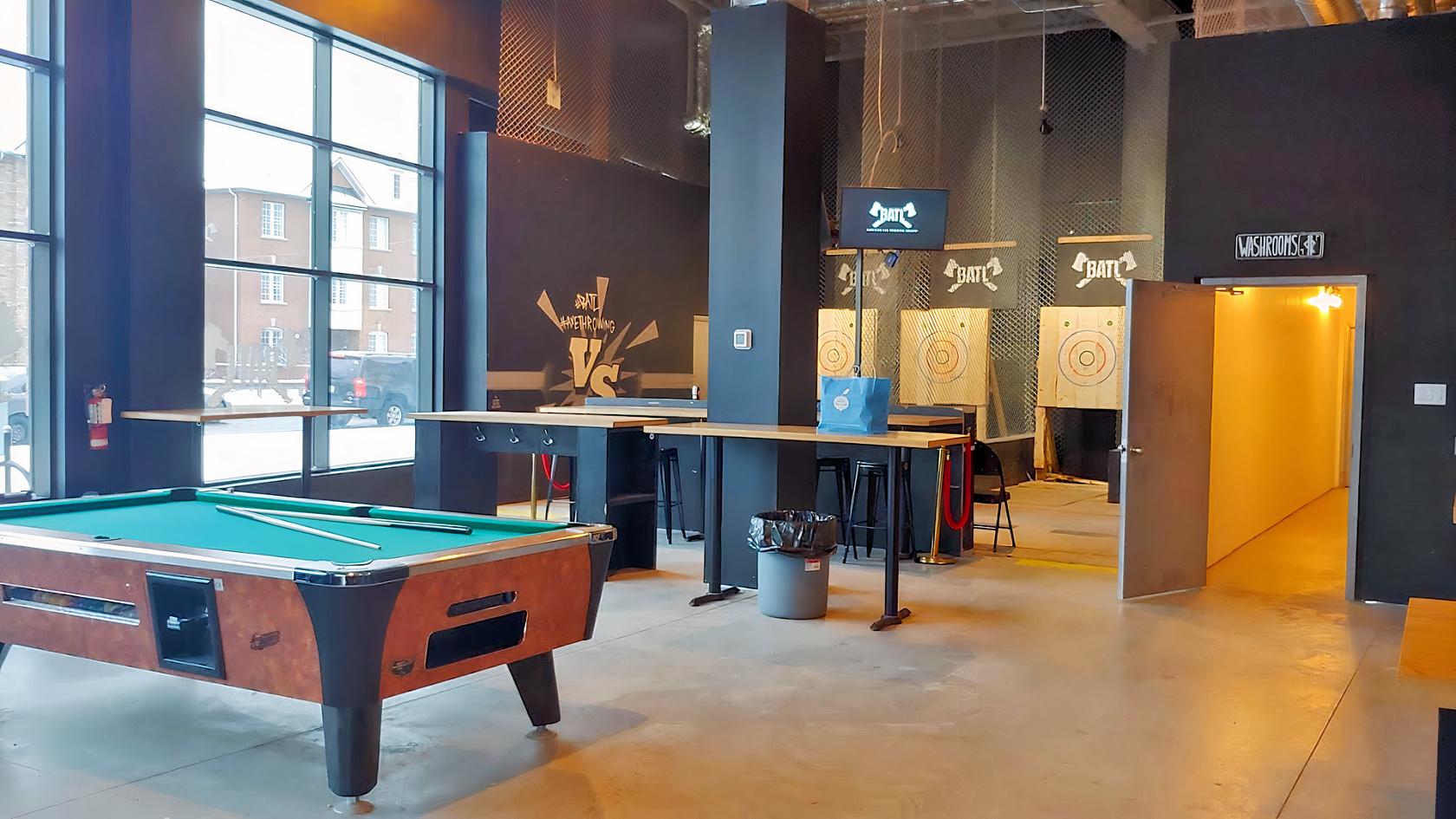 An entertainment centre with axe throwing lanes, high tables, and a pool table at BATL Grounds Stockyards.