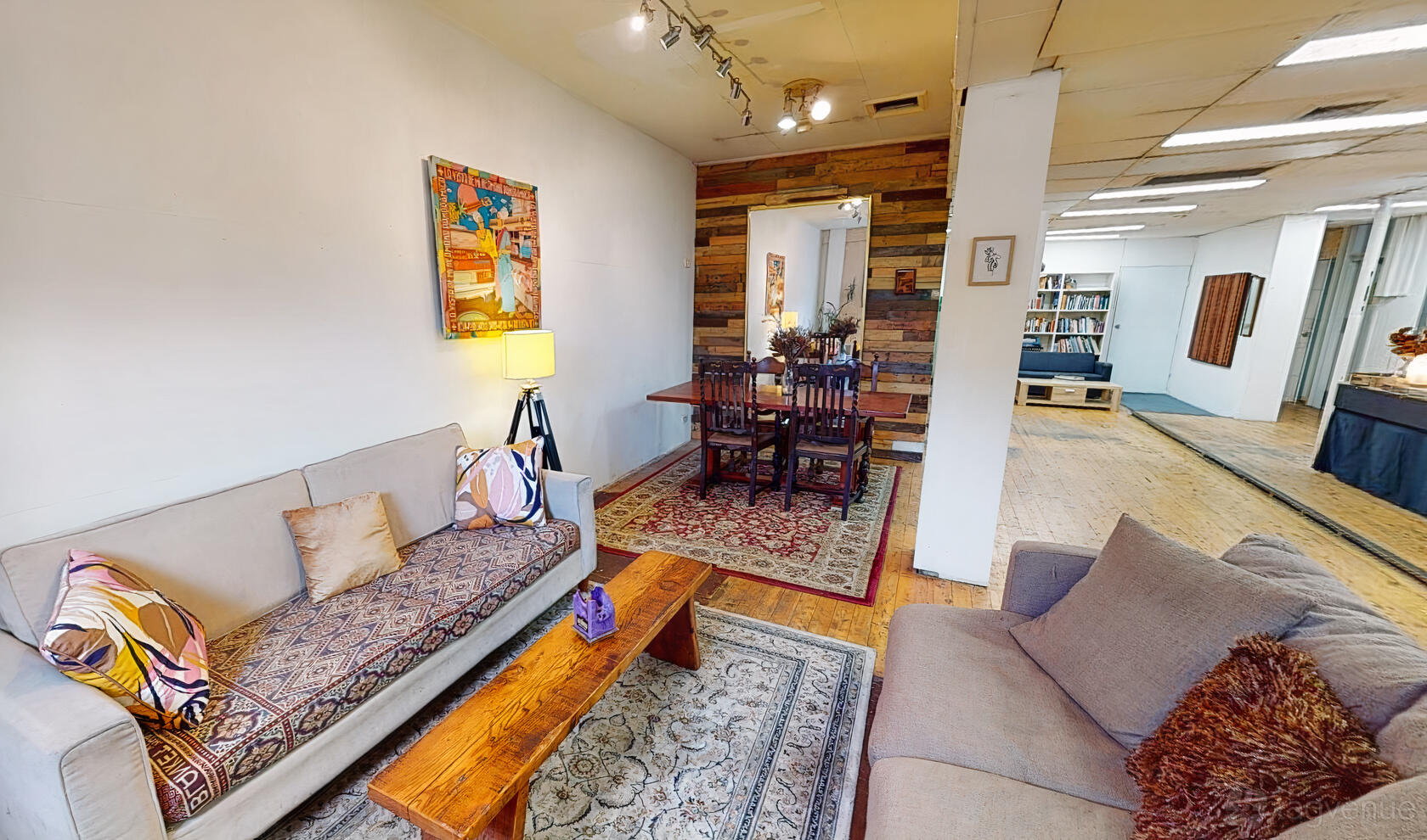 An event space in a gallery with sofas, patterned rugs, a wooden coffee table, and wall art at Flow Studios.