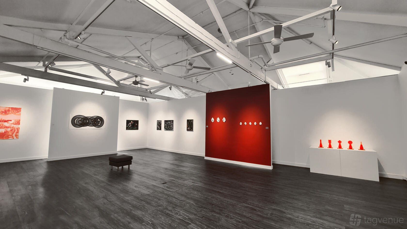 A gallery with white walls, exposed ceiling beams, track lighting, and contemporary artwork at Exhibition space @Chippendale.