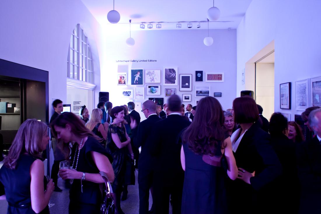 An art gallery event space with framed artworks, white walls, and globe pendant lights at Whitechapel Gallery.