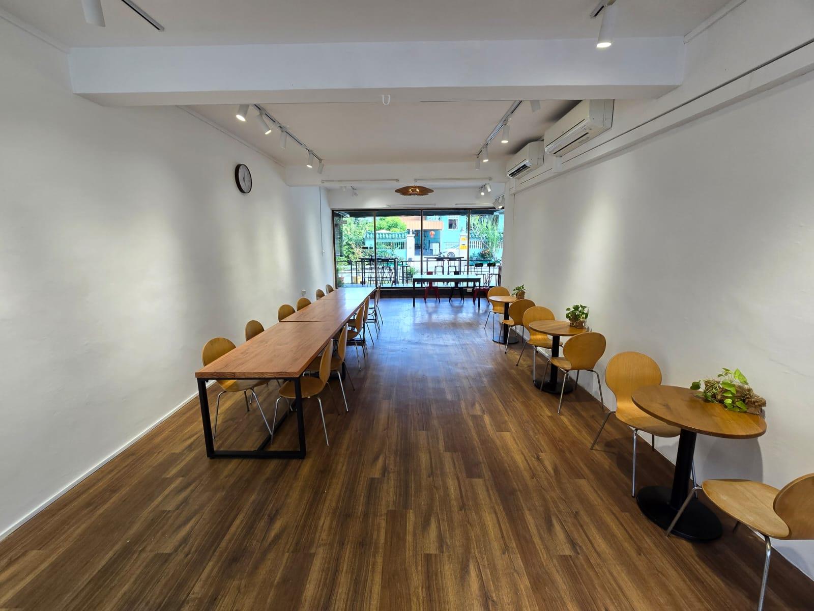 A dining room with long wooden tables, modern chairs, and floor-to-ceiling windows at The Garden Slug Family Restaurant.