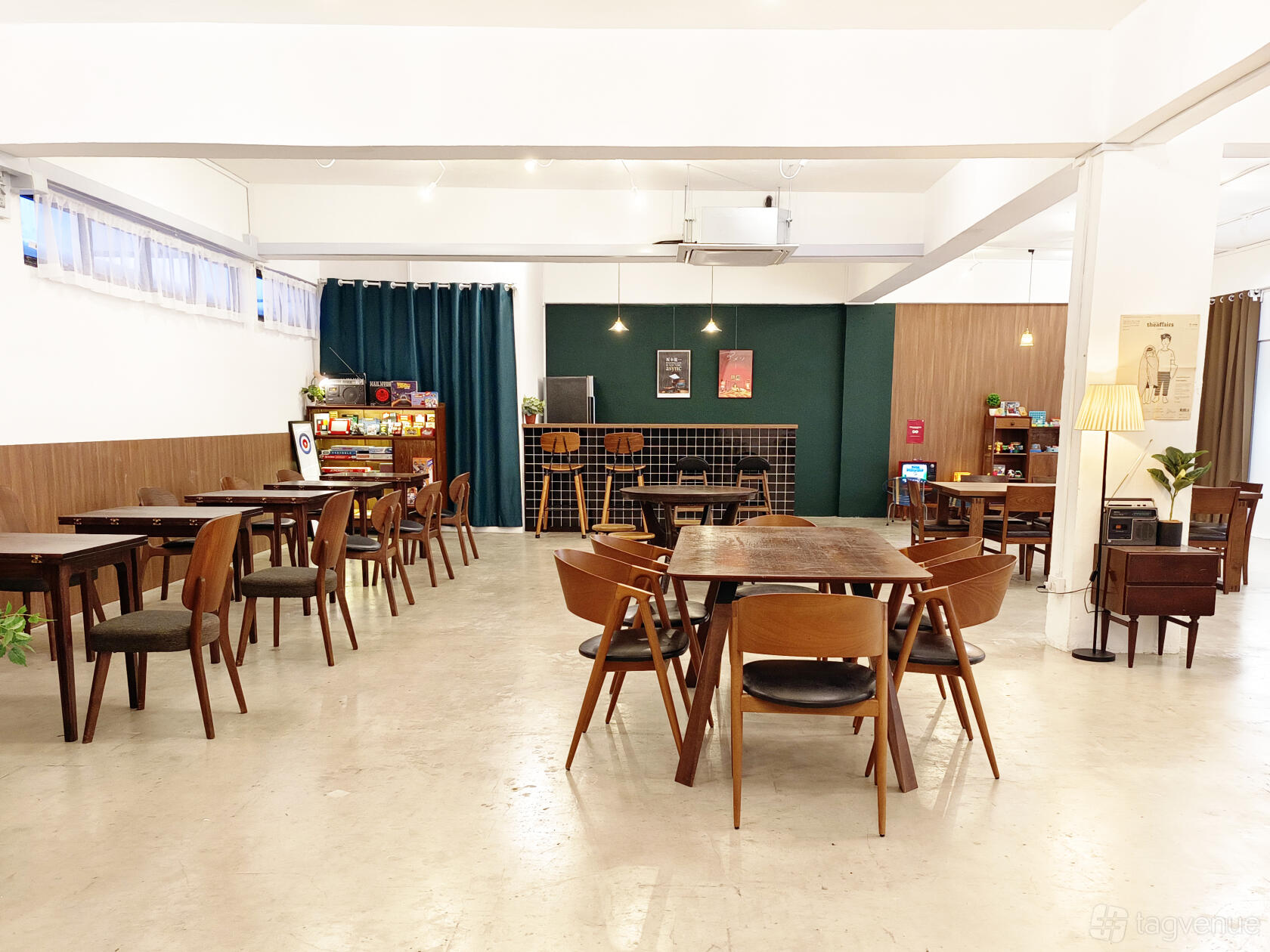 An event venue with vintage wooden chairs, square tables, retro decor, and natural light at room2f at Bras Basah Complex.