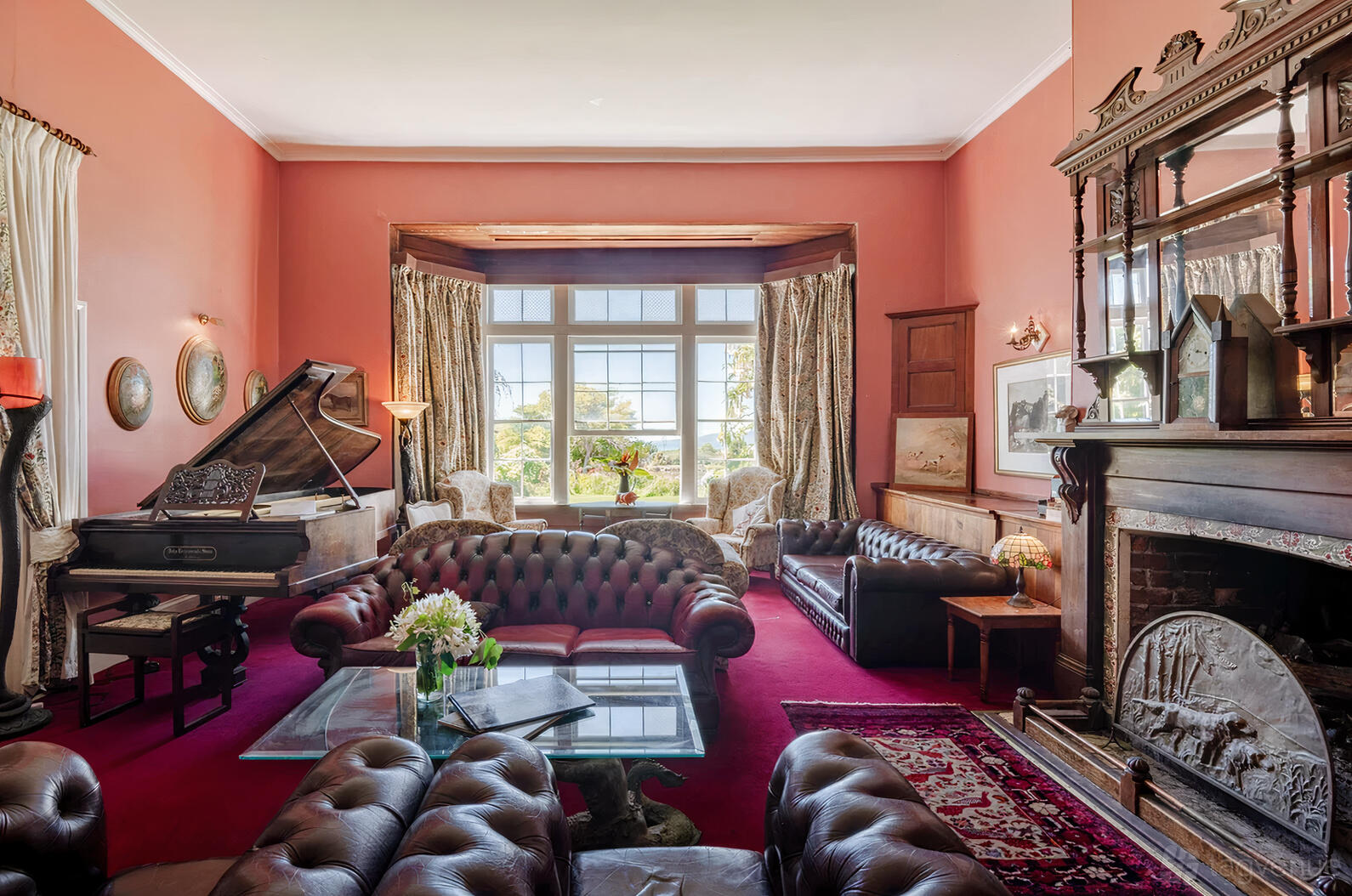 A country house with tufted leather sofas, a grand piano, and large bay windows at Hawley House.
