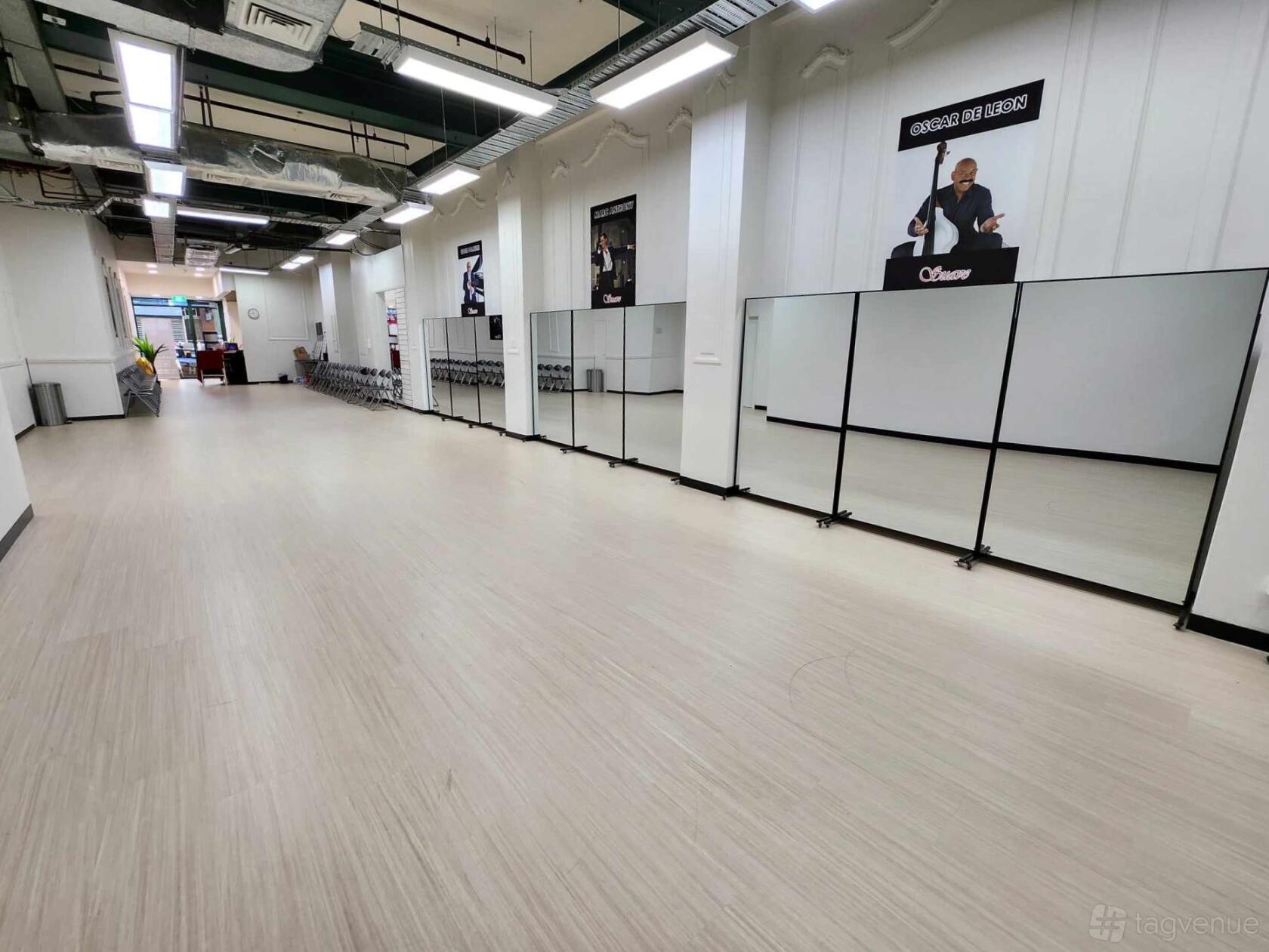 A dance studio with full-length wall mirrors, light wood flooring, and rows of chairs at Suave Dance Studio.