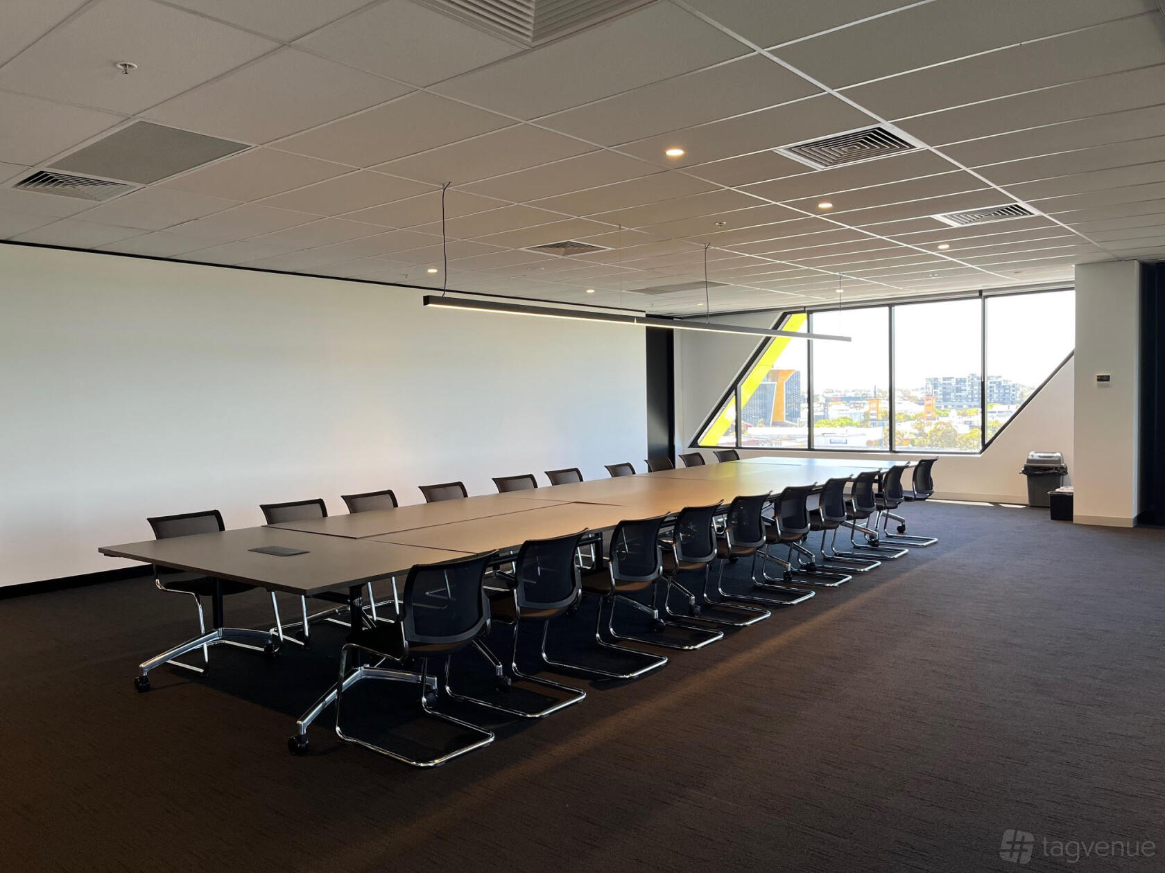 A training room with a long conference table, black chairs, and large windows at The Work Studio.