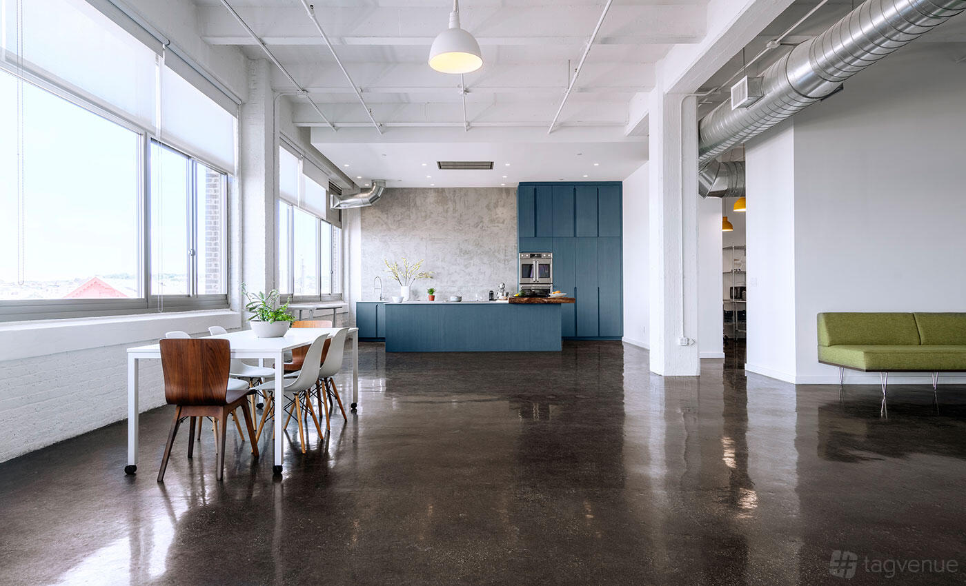A photo studio with a spacious kitchen setup, polished floors, large windows, and a blue cabinetry island at Cooktop Studio.