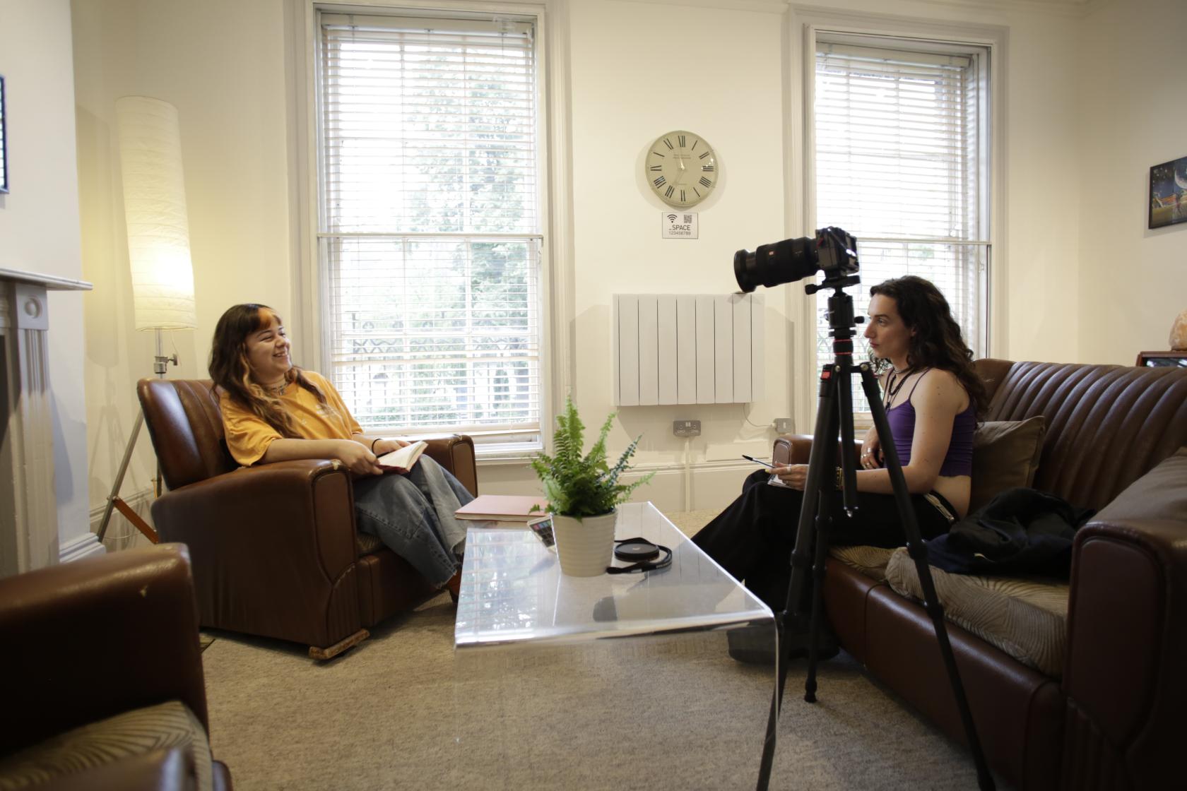 A function room with large windows, leather armchairs, and a wall clock at Anomalous Space.