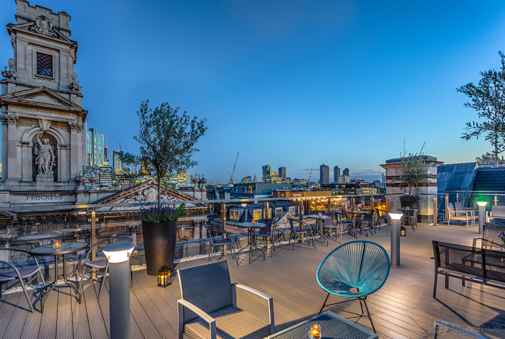A hotel terrace with city skyline views, modern outdoor seating, and potted trees at Courthouse Hotel Shoreditch.