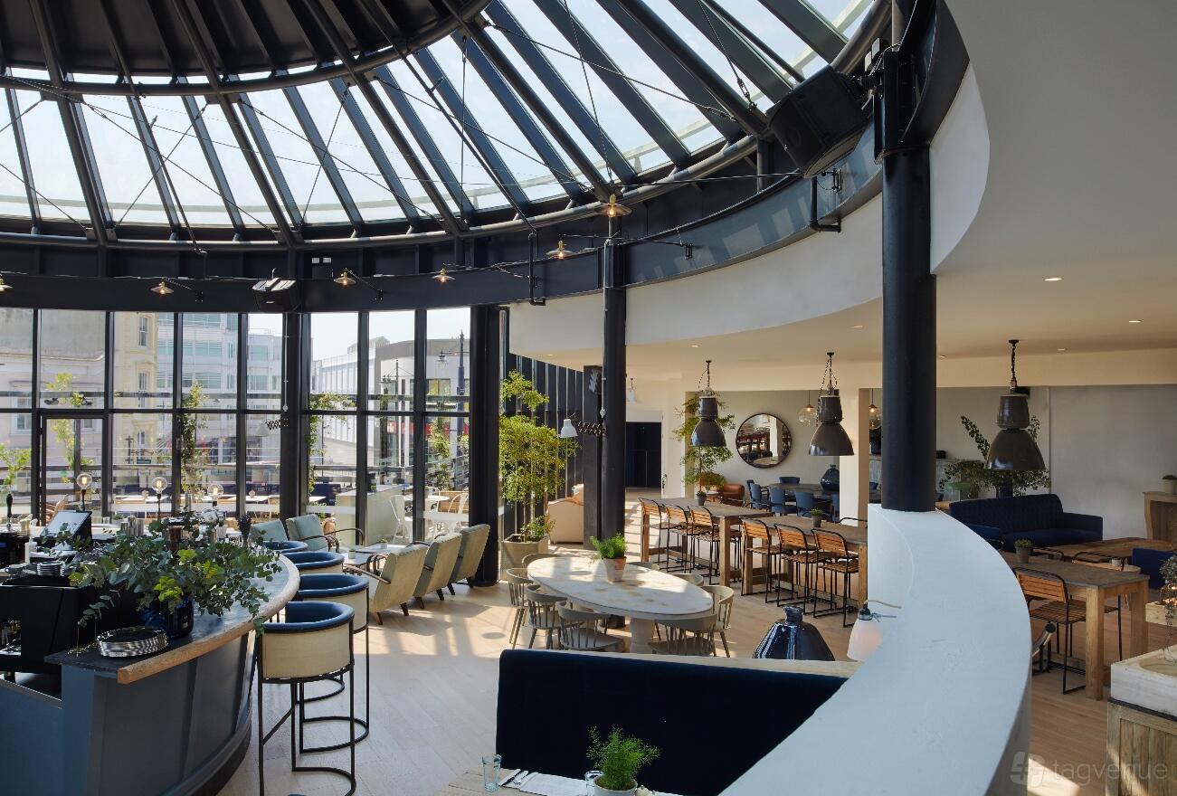 A cocktail bar with floor-to-ceiling windows, skylight ceiling, and mixed lounge seating at 601 Queen's Road.