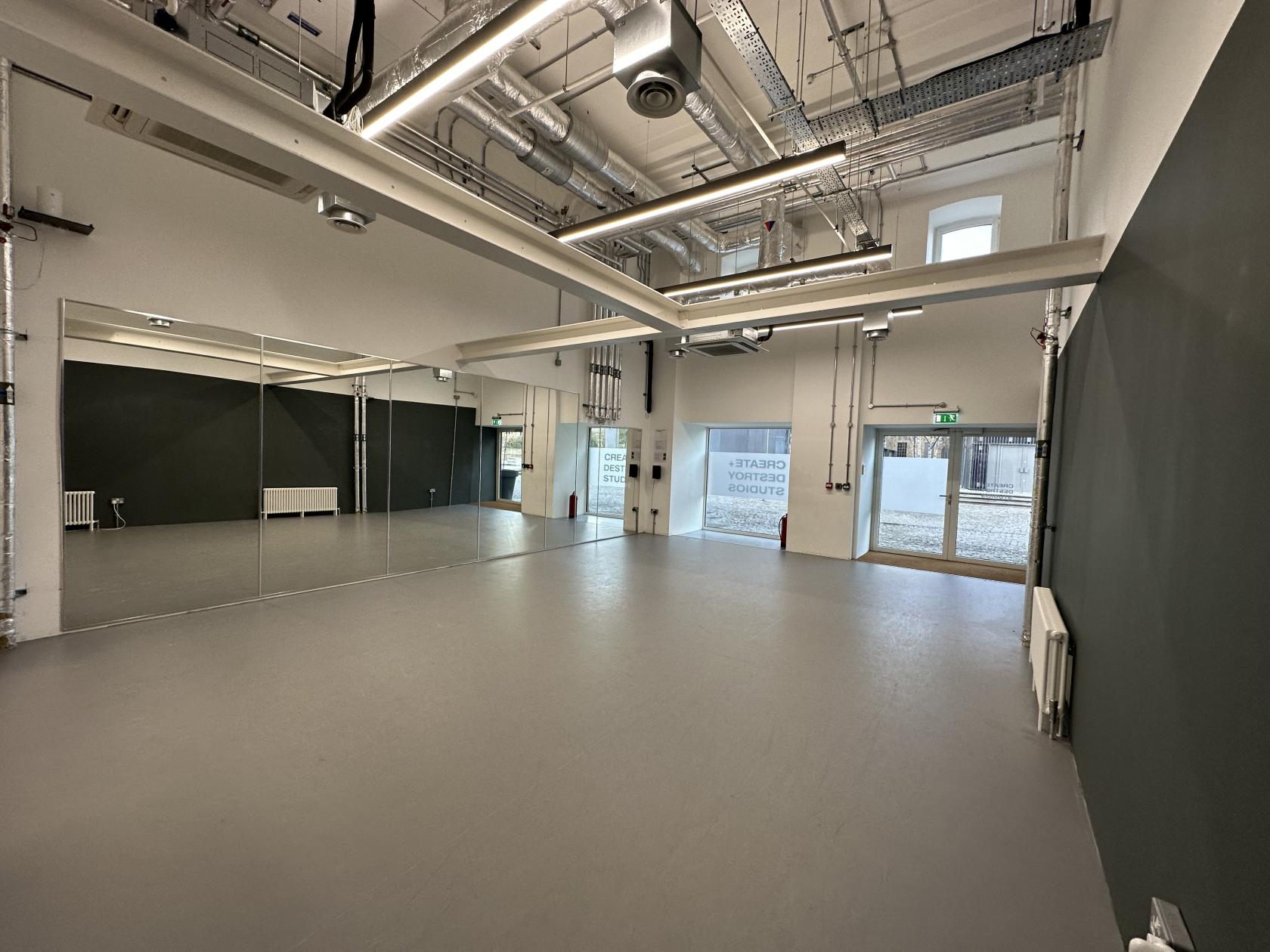 A dance studio with mirrored walls, exposed ductwork, and large windows at Sugar House Island.