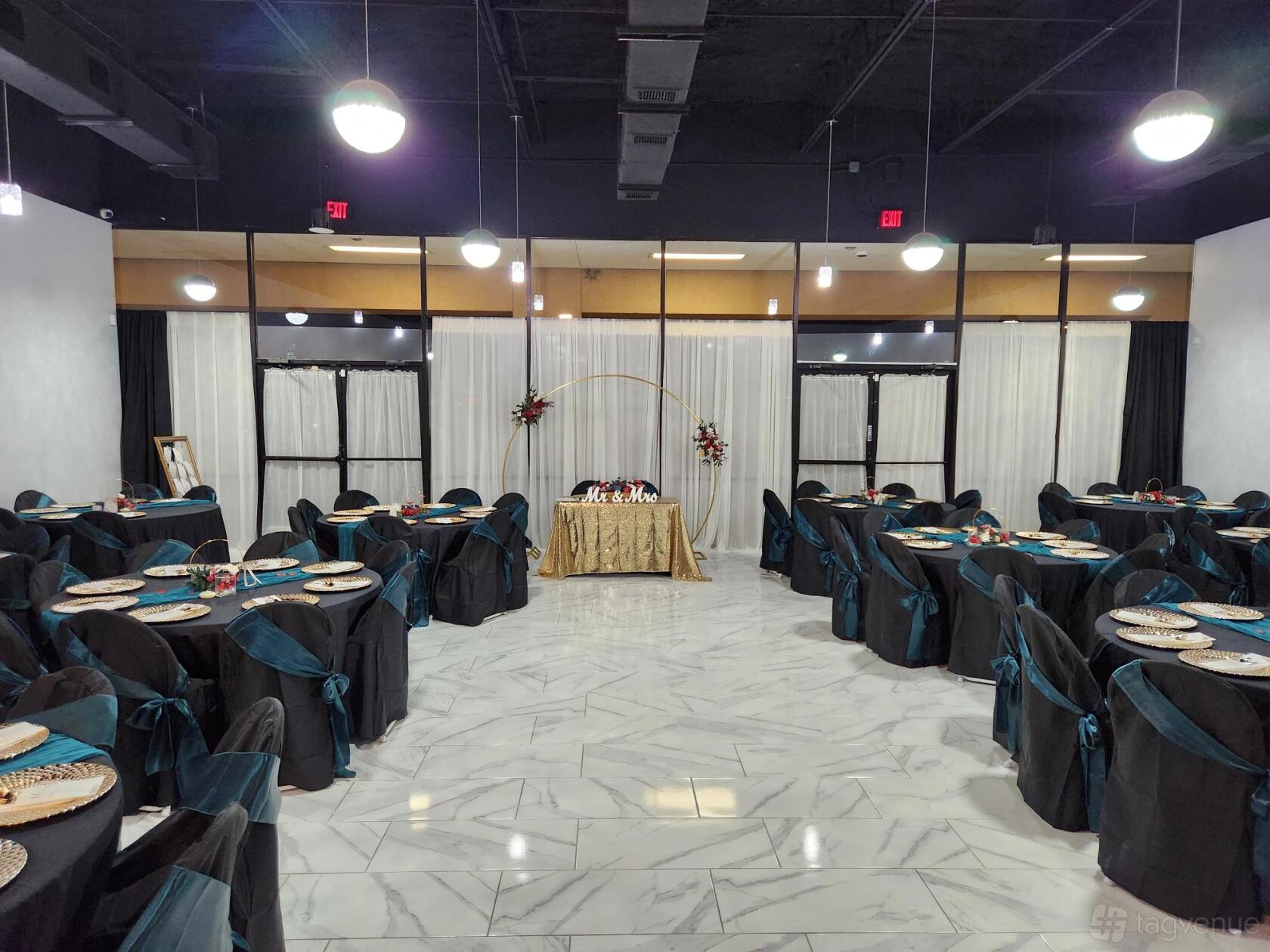 An event venue with marble flooring, round tables draped in black and teal linens, and a sweetheart table at Exquisite Elegance Event Center.