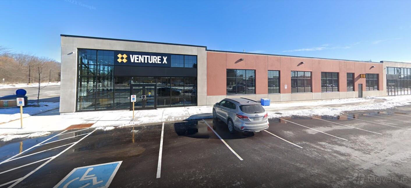A coworking space with large floor-to-ceiling windows and brick exterior at Venture X South Oak Junction.