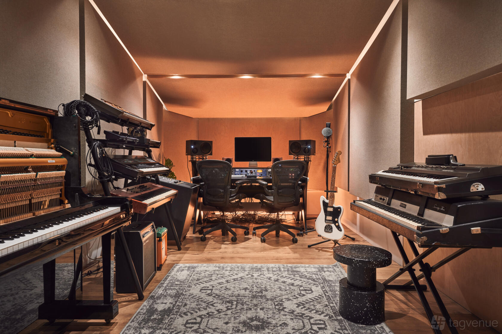 A music studio with multiple keyboards, a mixing console, studio monitors, and acoustic panels at Ten87 Studios.