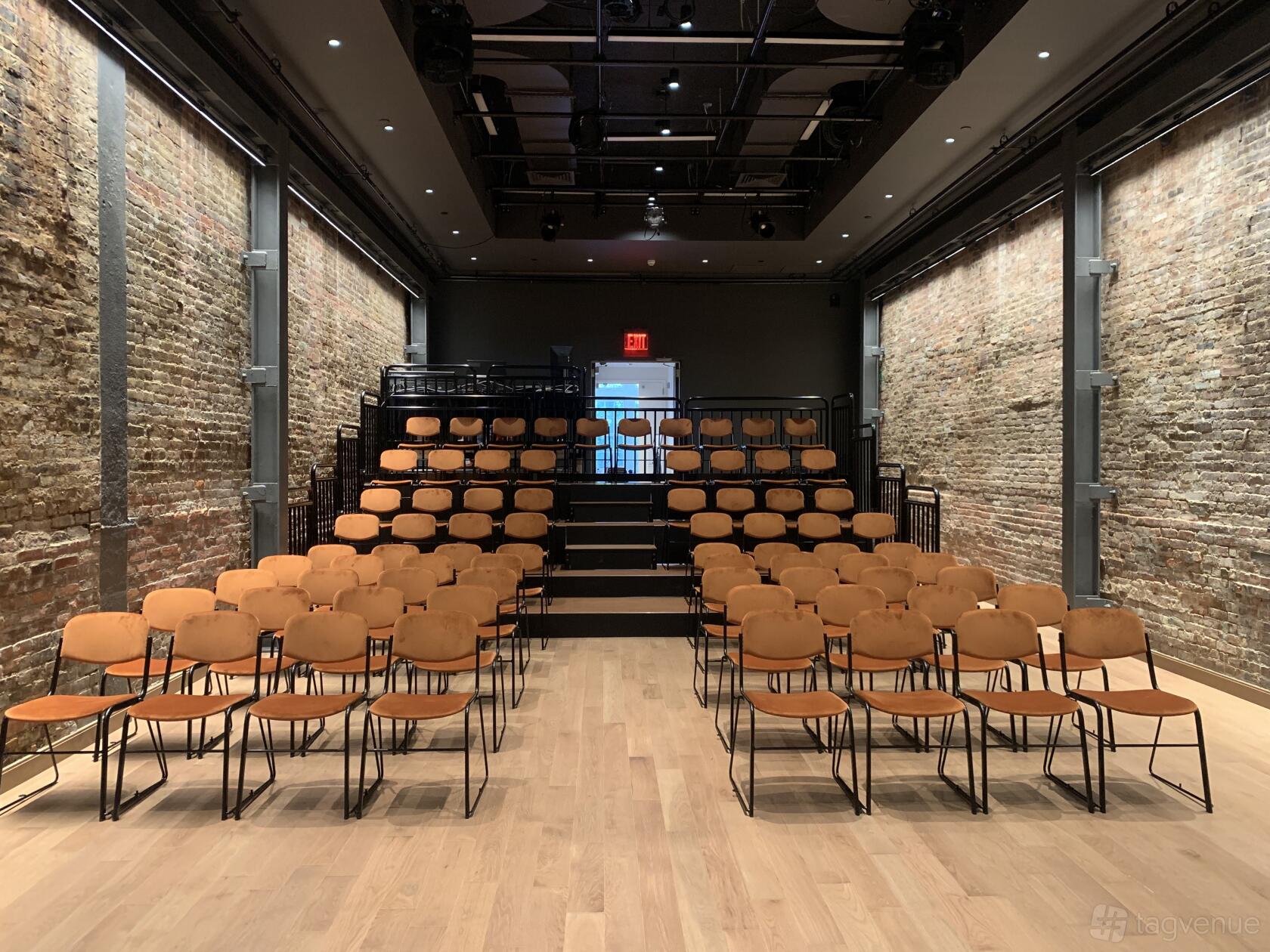 A theatre with exposed brick walls, wooden floors, and tiered seating at La MaMa Experimental Theatre Club.
