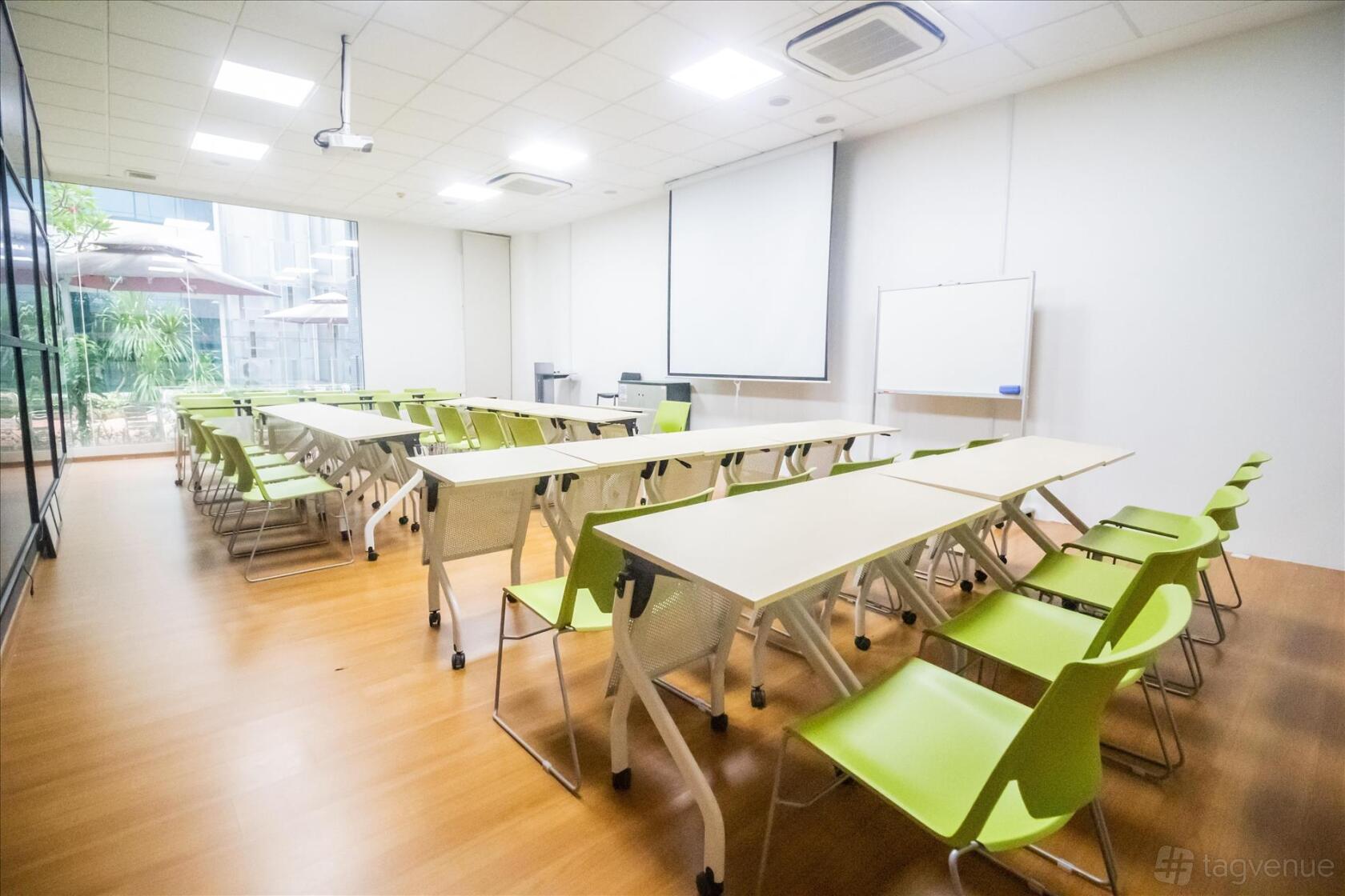 A classroom with green chairs, light wood tables, a projector, and floor-to-ceiling windows at ERC Institute.