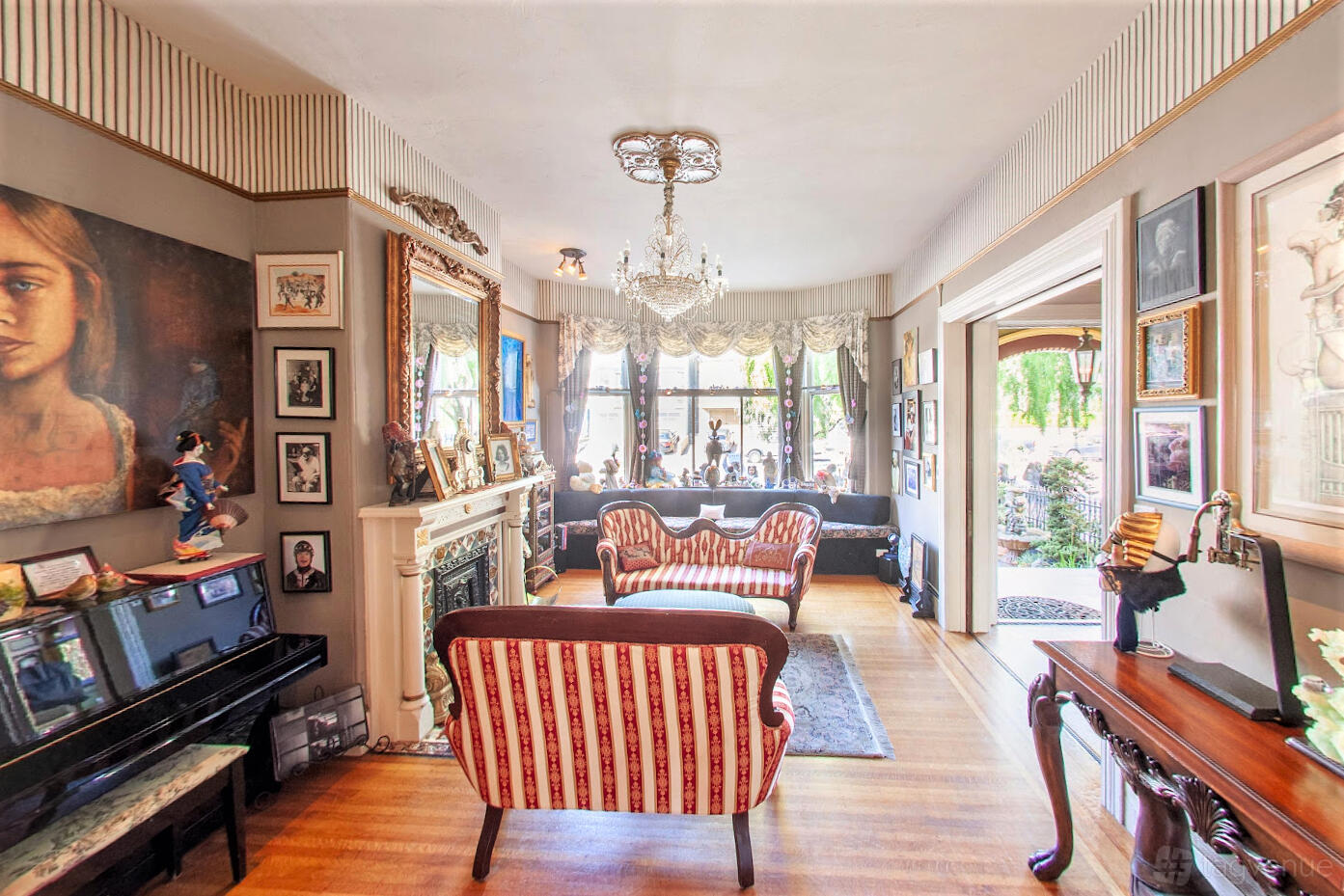 A hotel lounge with striped antique sofas, a chandelier, ornate fireplace, and large windows at Noe's Nest.