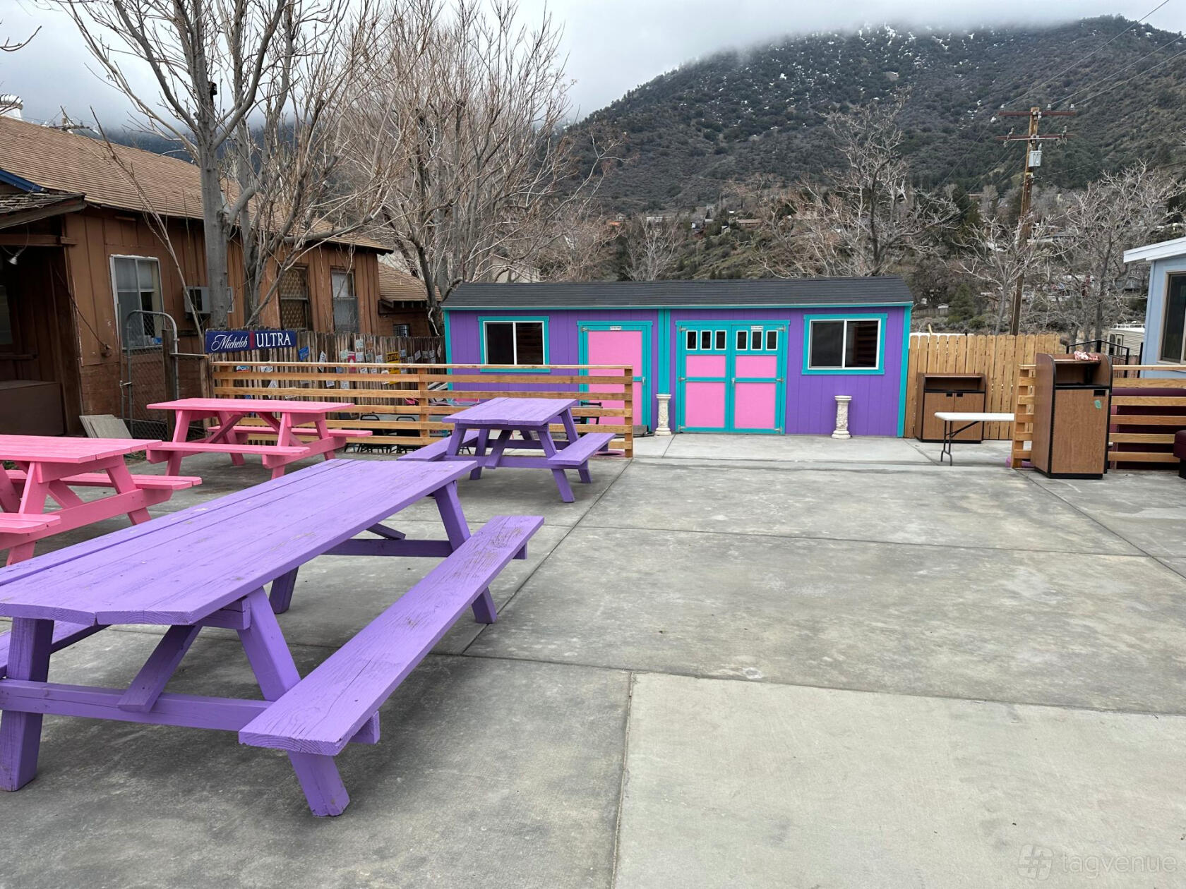 An outdoor venue with colorful picnic tables, wooden fences, and a small building at The Oak Pit Event and Artist Venue.