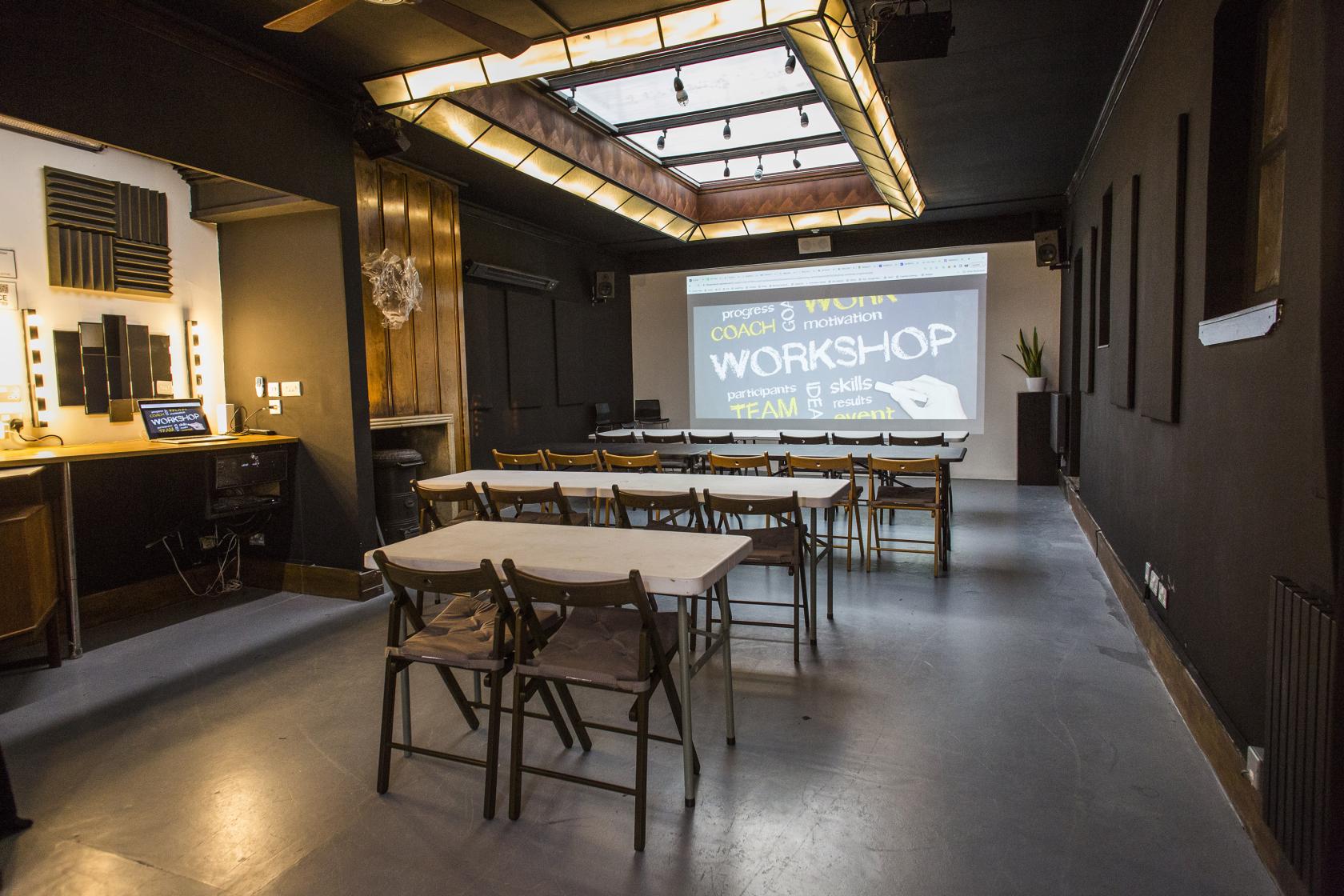 An event space with folding chairs, rectangular tables and a skylight ceiling at Anomalous Space.