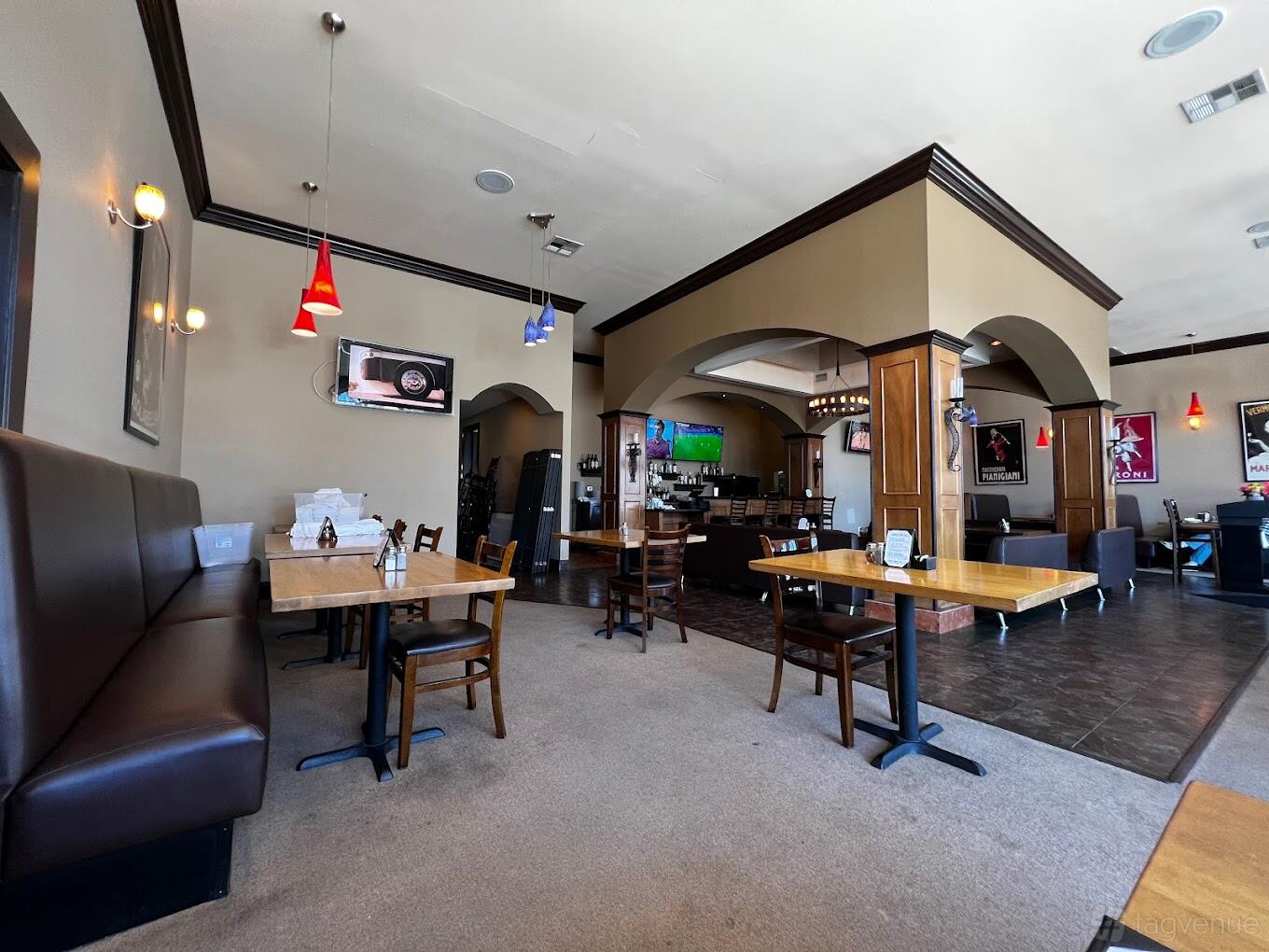 A restaurant dining area with wooden tables, booth seating, pendant lights, and wall-mounted TVs at Pinocchio's Pizza.