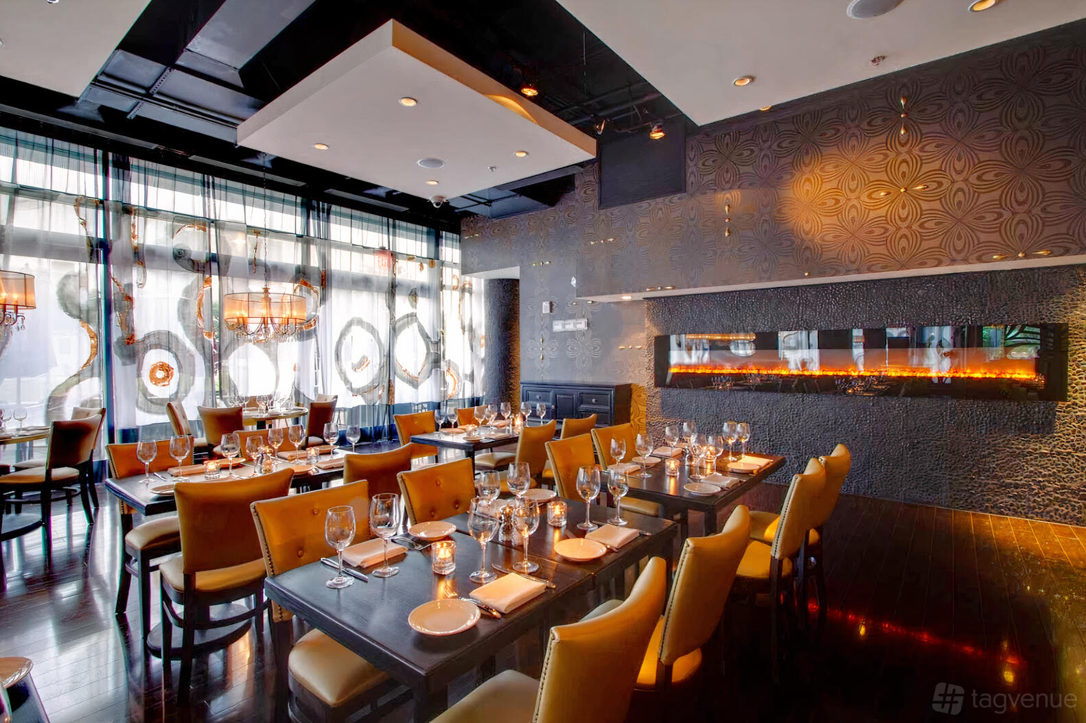 A restaurant with floor-to-ceiling windows, patterned feature wall, and long tables set for dining at Station 4.