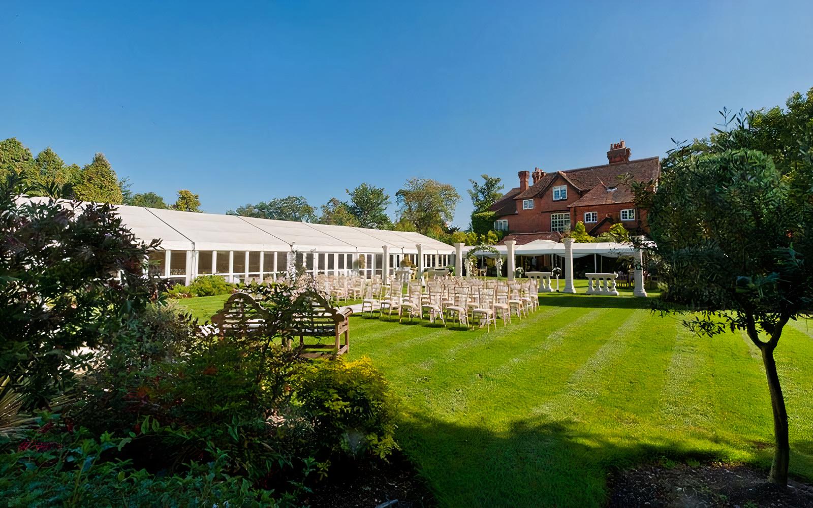 An event lawn with rows of white chairs, a large marquee tent, and manicured gardens at Trunkwell House Hotel.