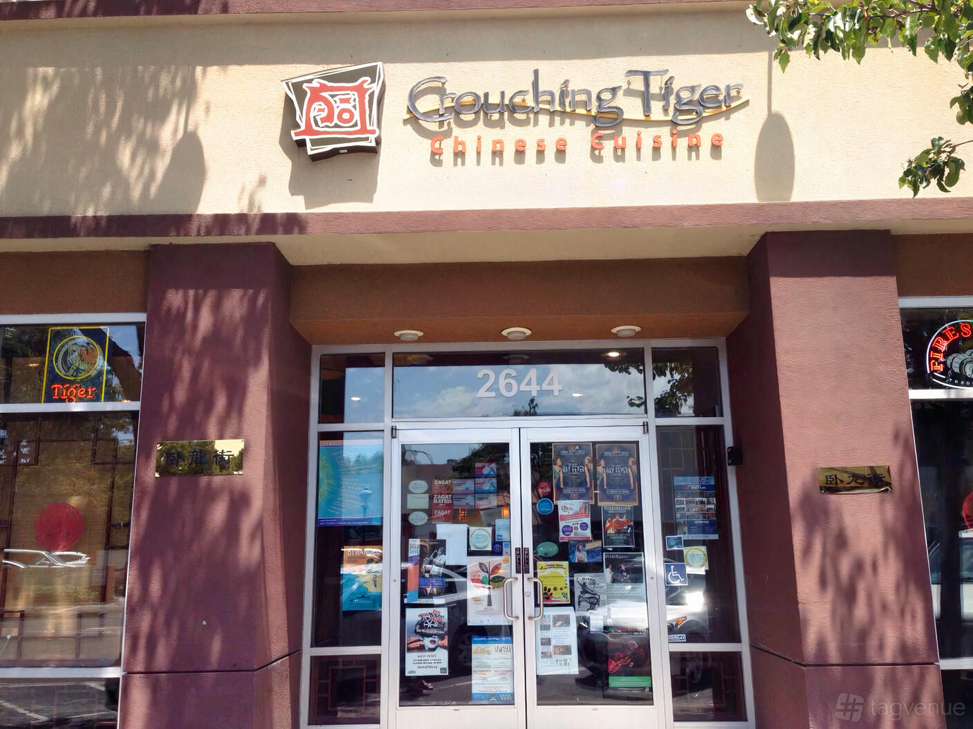 A restaurant exterior with glass doors, window posters, and a sign reading Crouching Tiger Chinese Cuisine at Crouching Tiger Restaurant & Bar.