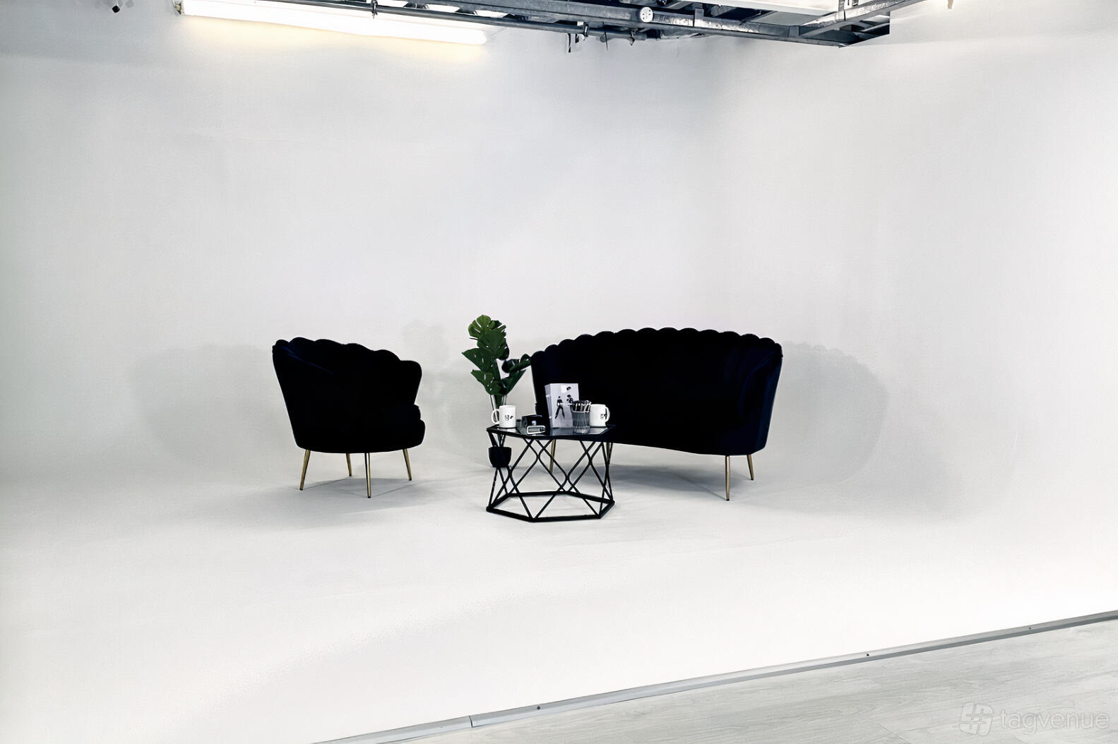 A photo studio with a white infinity cove, black velvet seating, and a geometric coffee table at A&B Films Studio.