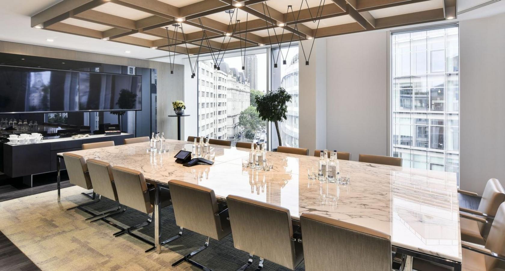 A meeting room with a marble conference table, floor-to-ceiling windows, and neutral chairs at Octagon Point St Paul's.