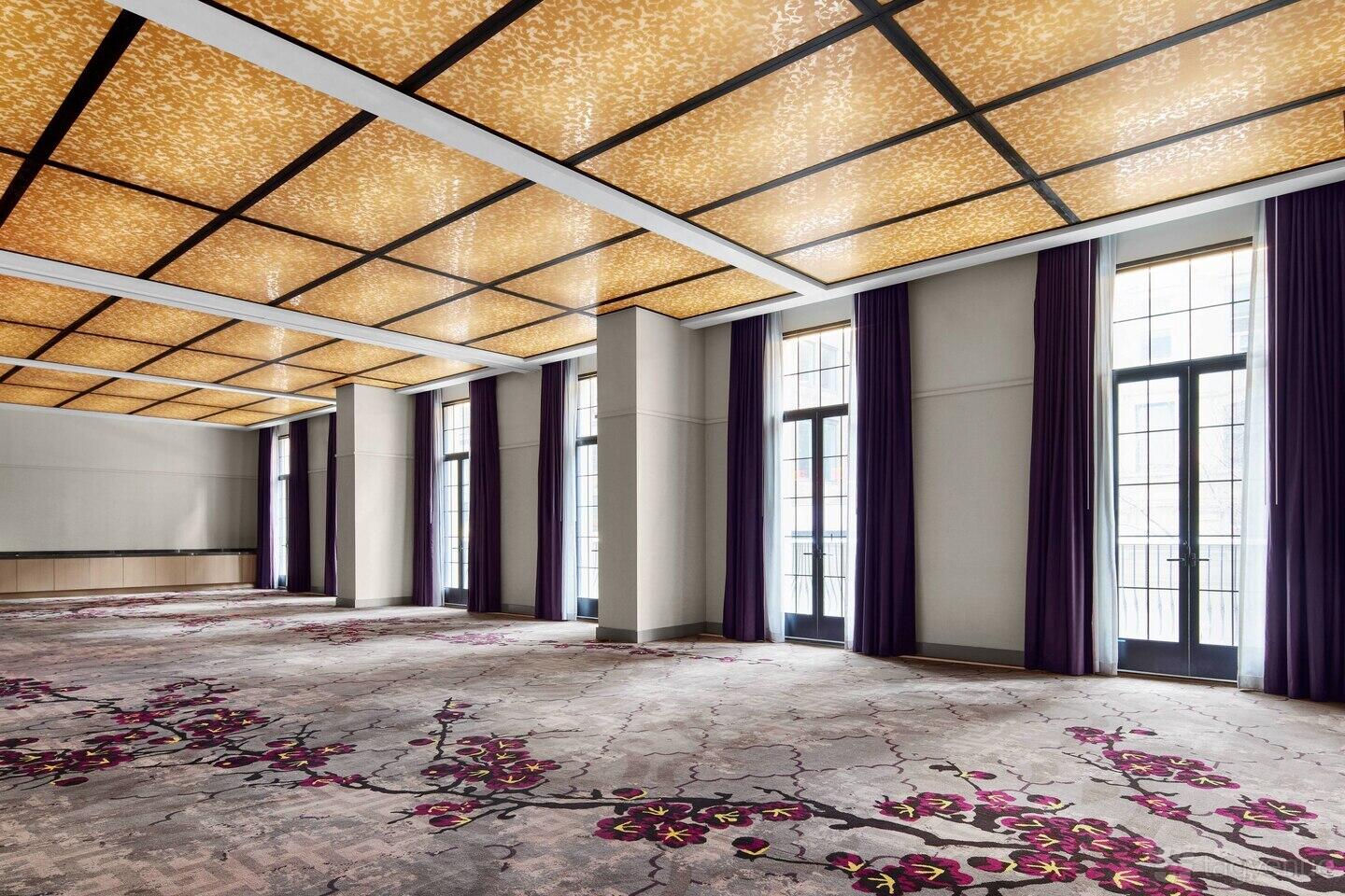 A restaurant event room with floor-to-ceiling windows, patterned carpet, and a backlit coffered ceiling at R Bar & Cafe.
