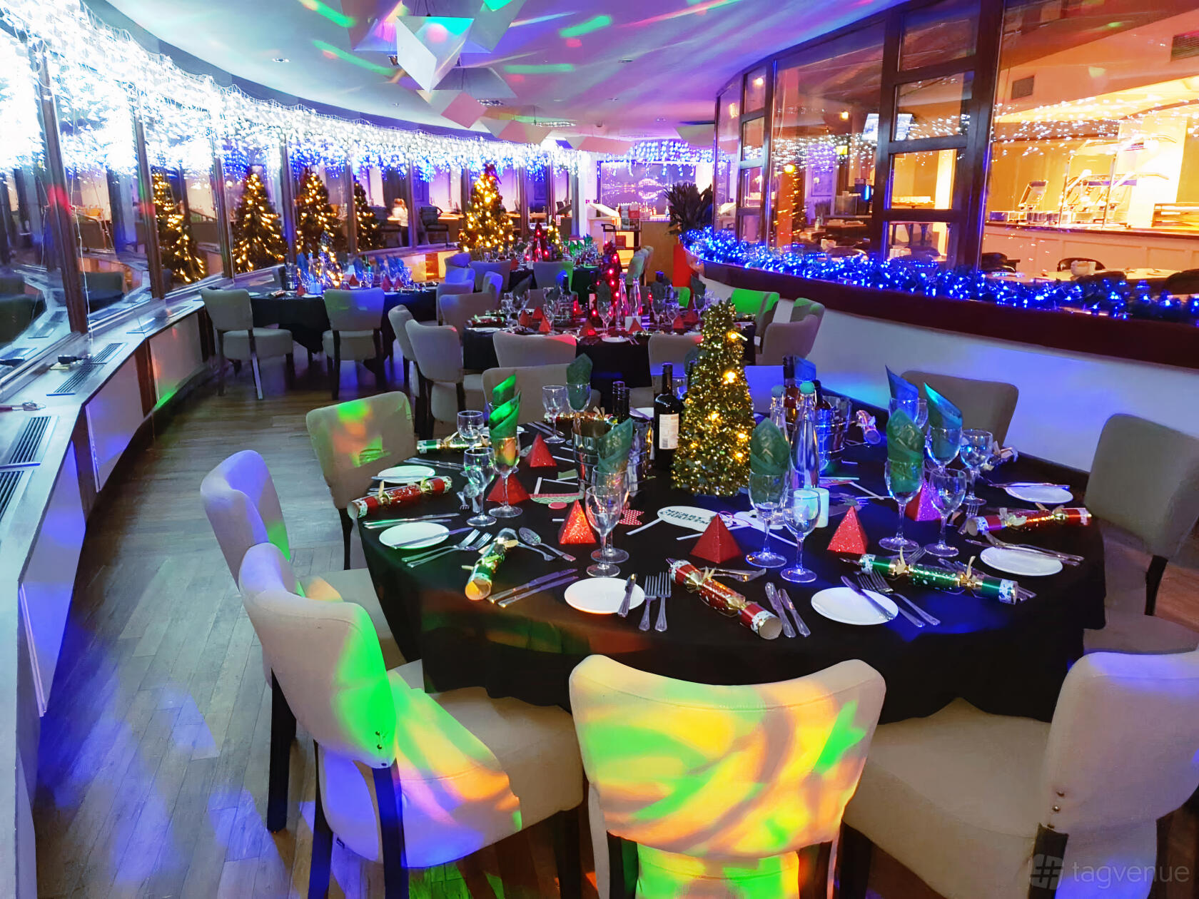 A restaurant with round tables dressed in festive decorations and colored lighting at Copthorne Hotel Manchester.