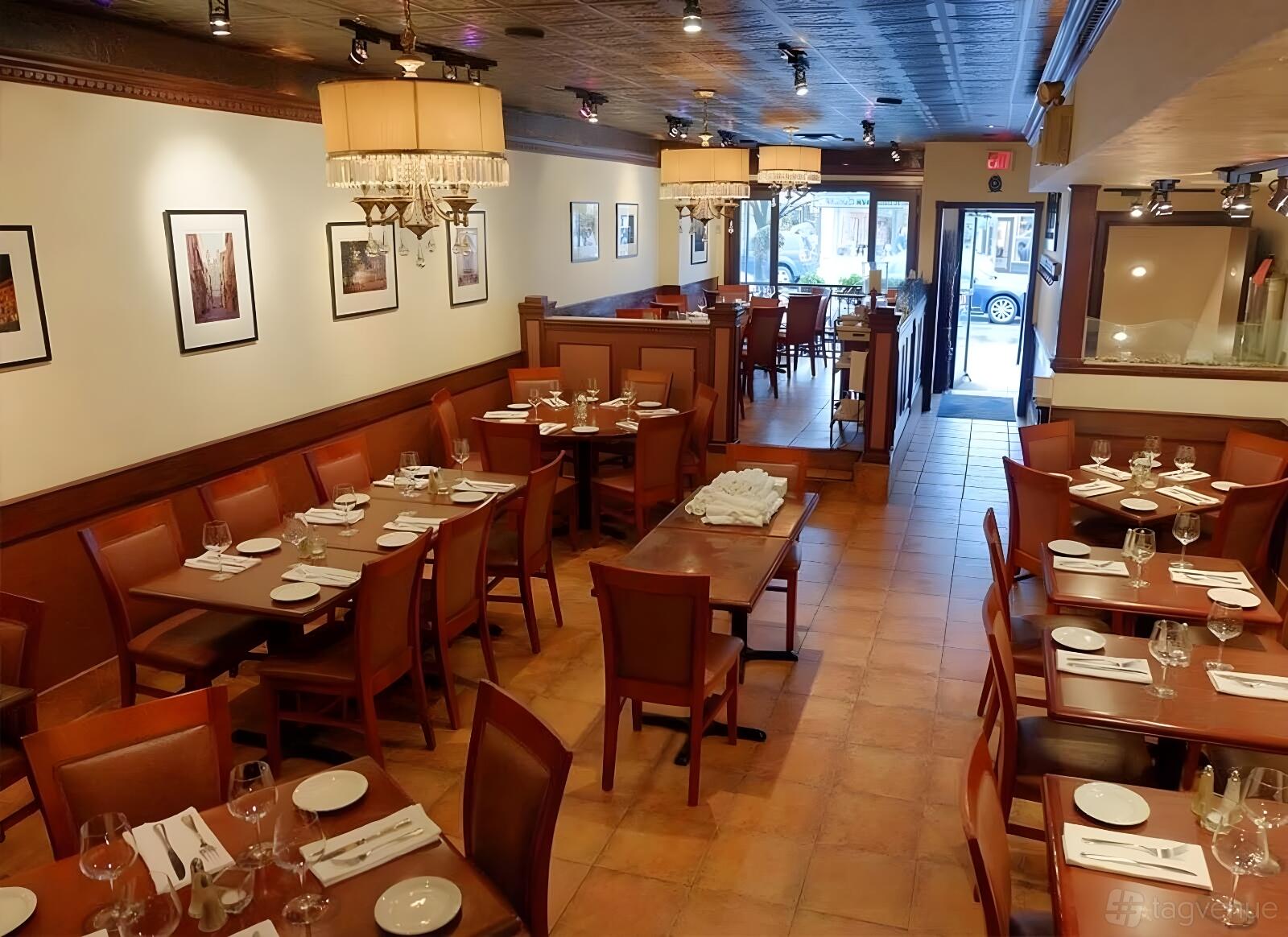A restaurant with wooden tables, matching chairs, tile flooring, and chandeliers at Buono Ristorante.