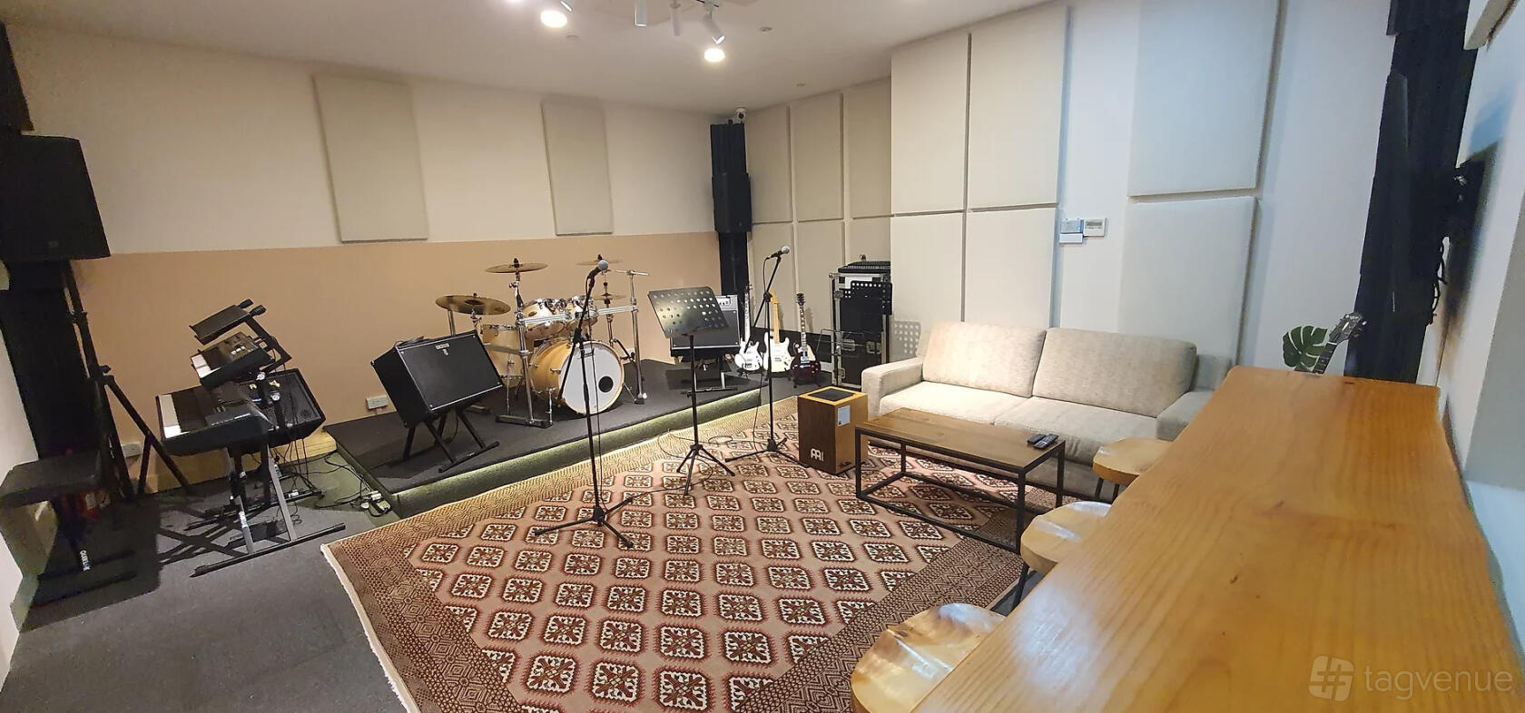 A music studio with drum kit, amplifiers, microphones, and a beige sofa at Rock Haven Studio.