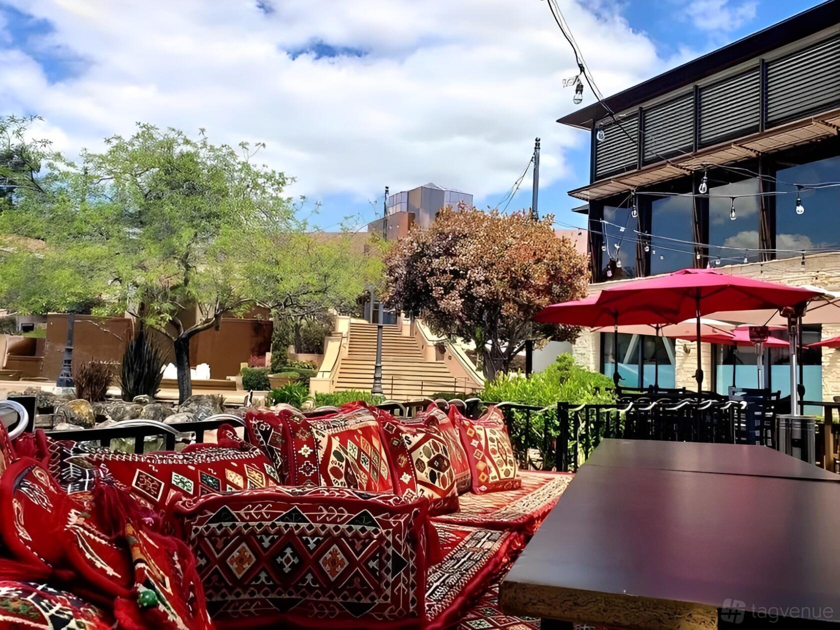 An outdoor patio at 786 Kabob House with patterned cushions, umbrellas, and string lights near desert landscaping.