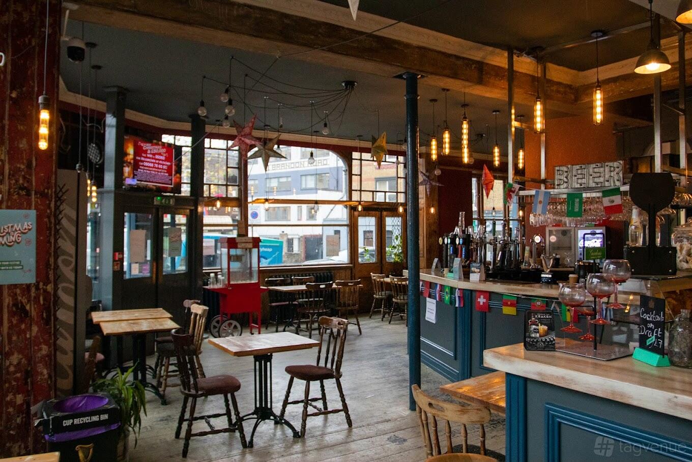 A hotel restaurant with large windows, hanging pendant lights, and a central bar at Newmarket Ale House, Hotel & Restaurant.
