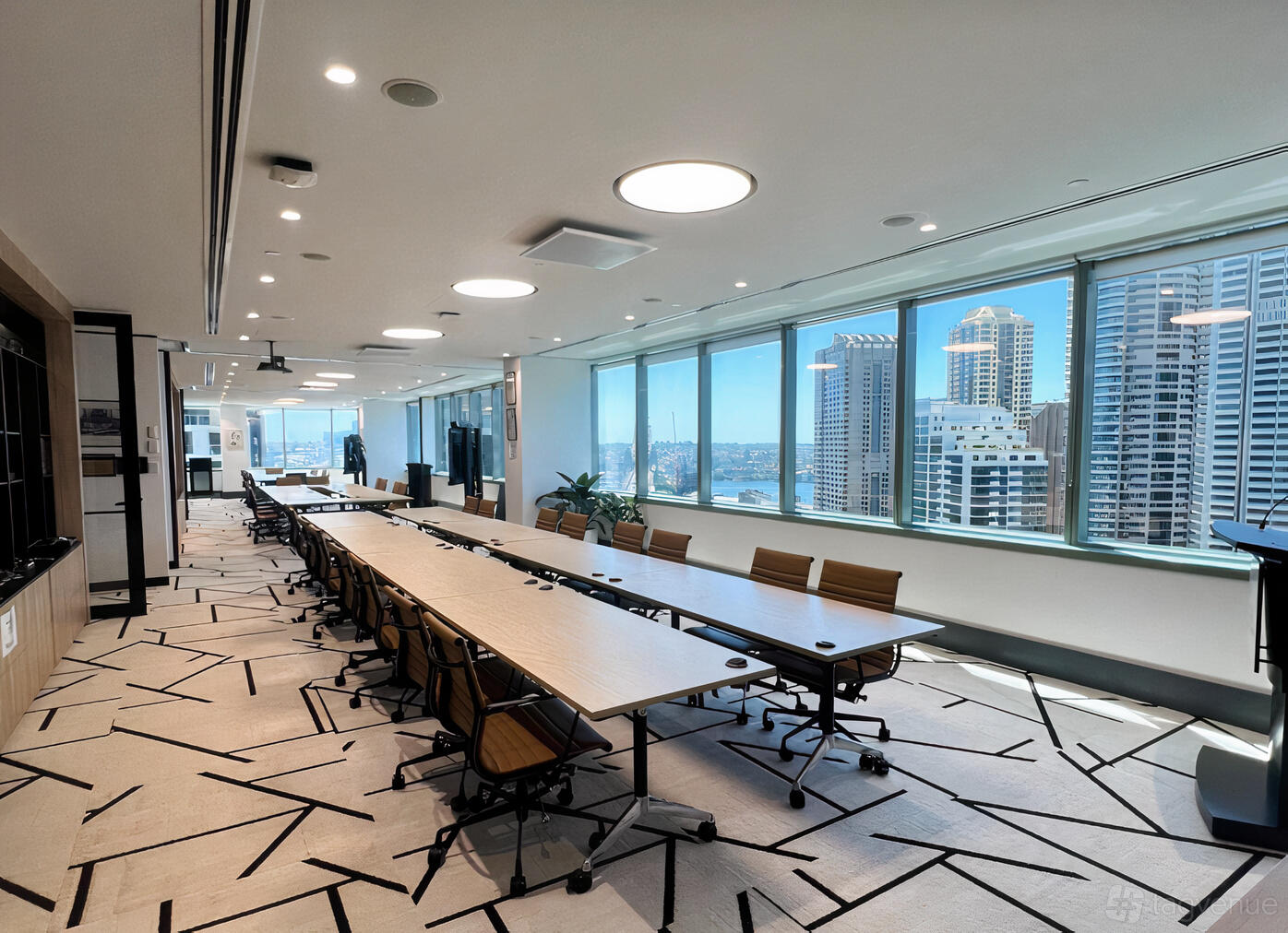 An event space with long conference tables, rolling chairs, and floor-to-ceiling windows overlooking the city at Royal Australasian College of Surgeons.