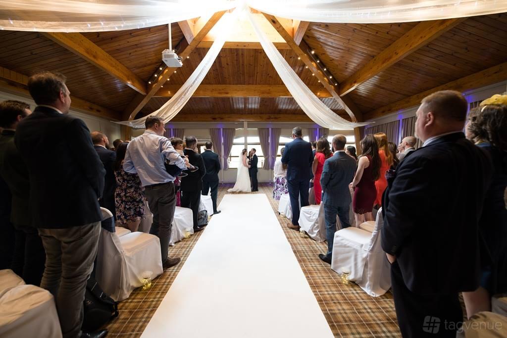 An event venue with exposed wooden beams, draped white fabric, and plaid carpeting at Woburn Safari Park Safari Lodge.