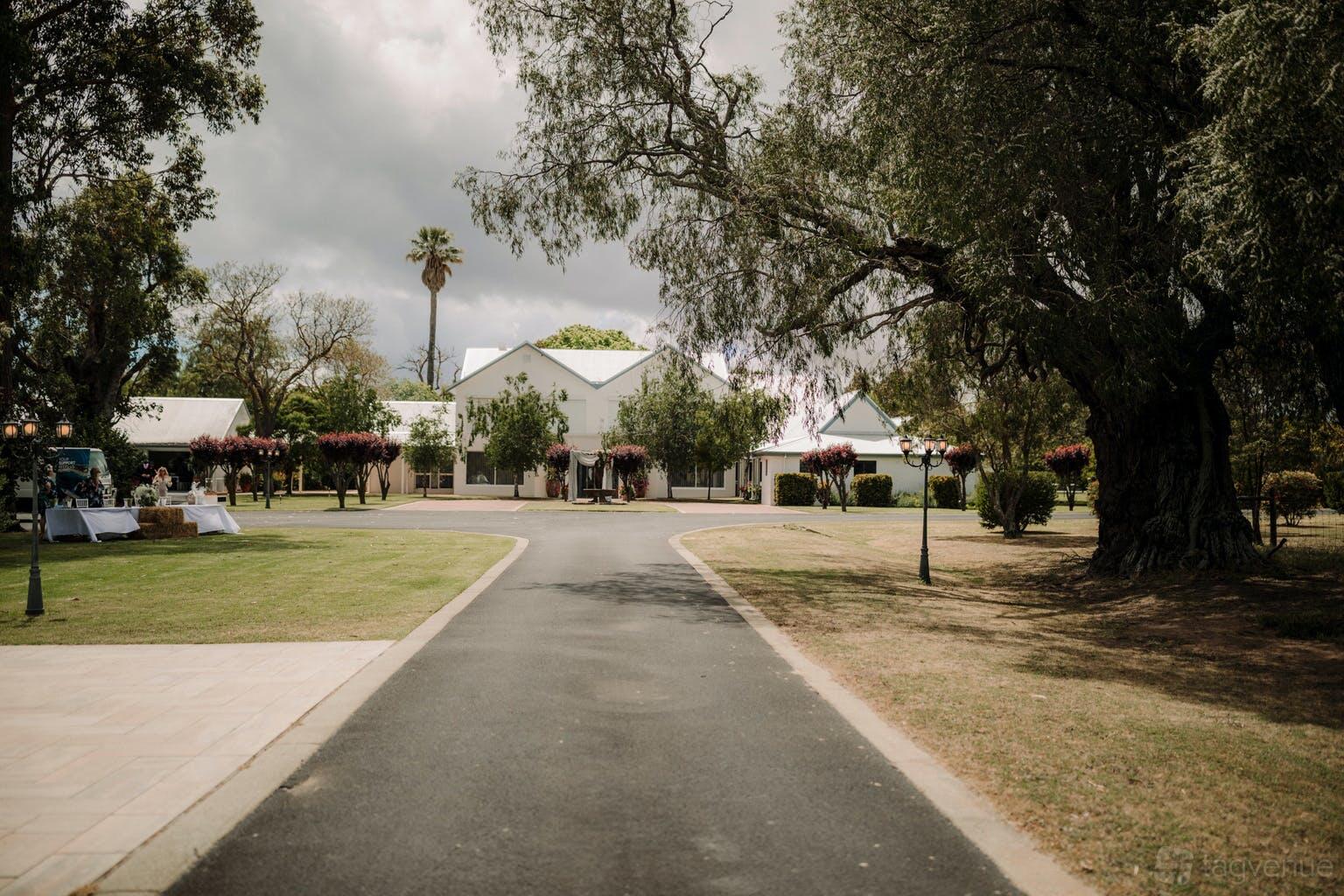 A historic building with white façades, tree-lined driveway, and manicured lawns at Fairlawn Estate.